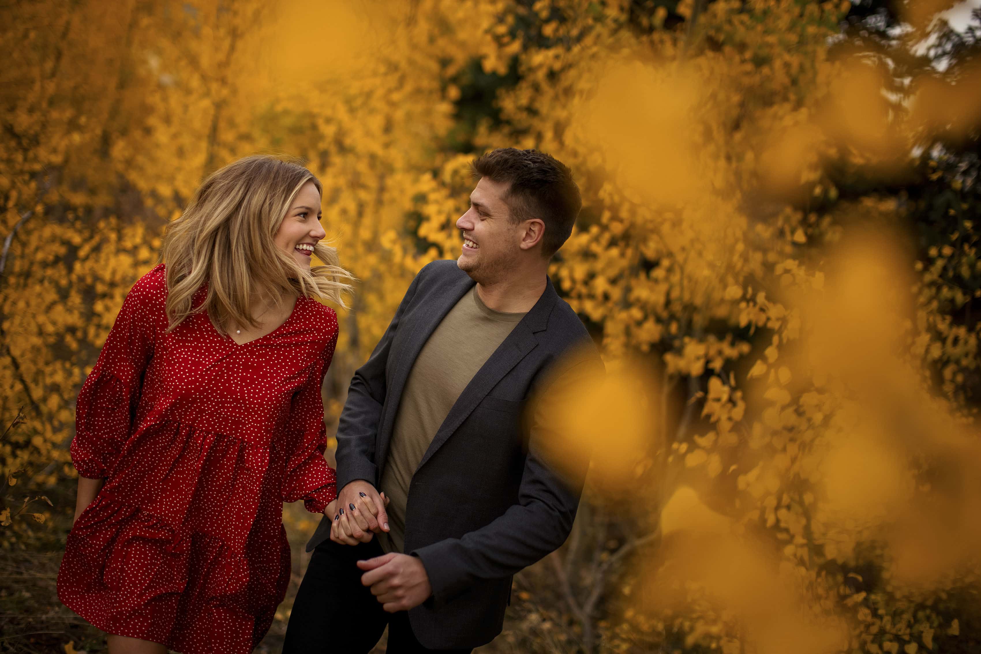 An engaged couple run in an aspen grove during their engagement photos