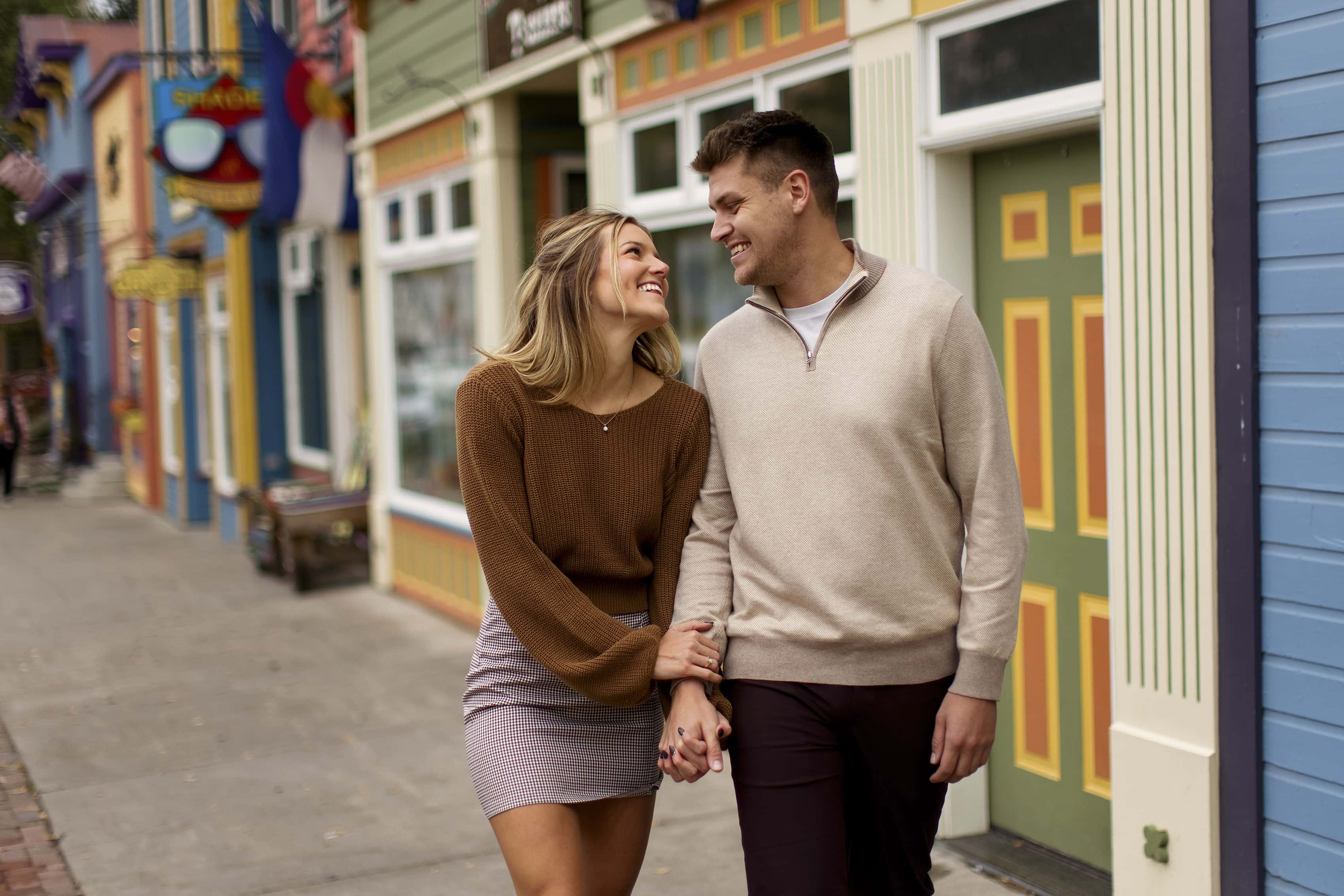 A couple walks in downtown Crested Butte during their engagement photos