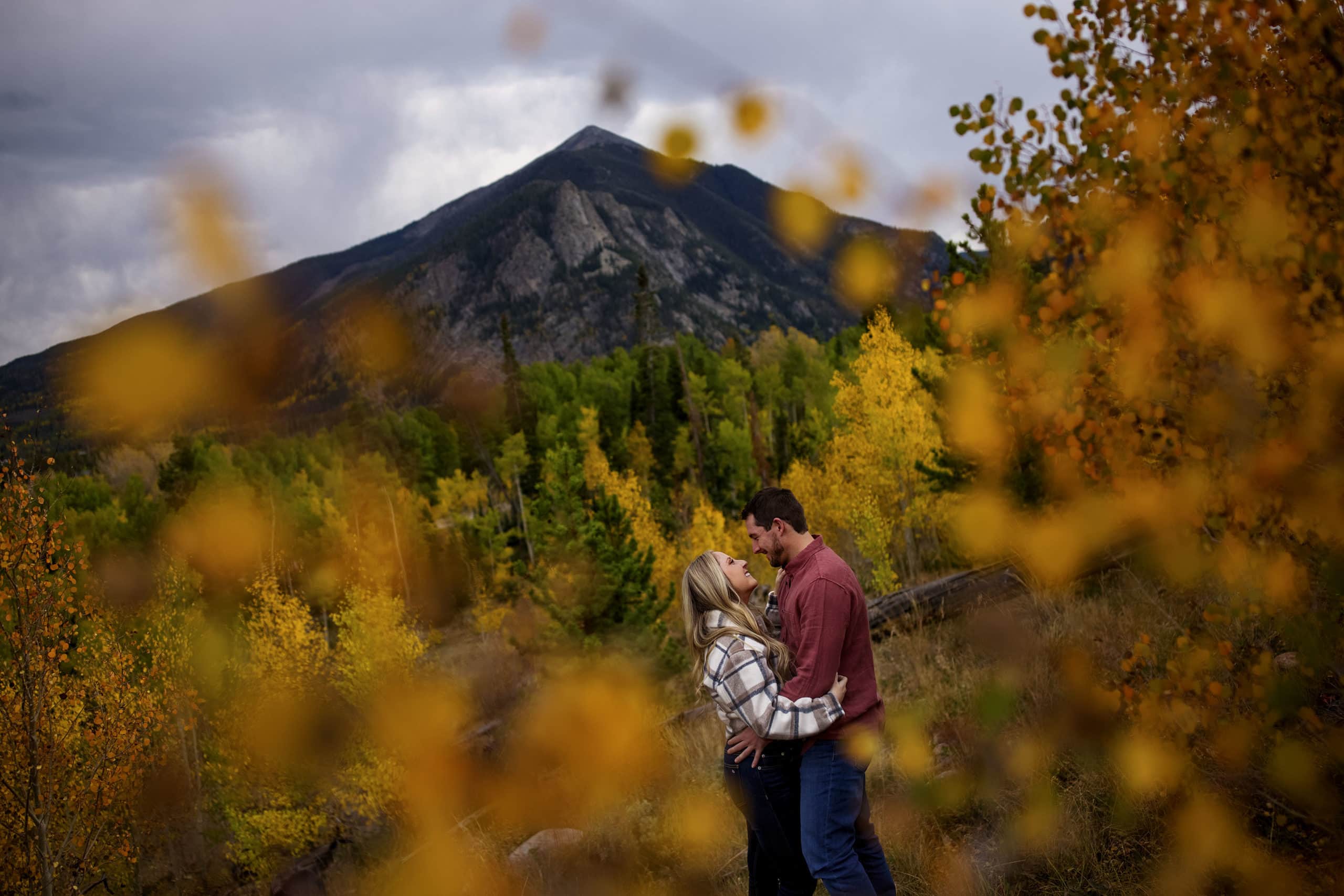 Jamie and Chad embrace near colorful aspen trees near Peak 1 in Frisco, Colorado