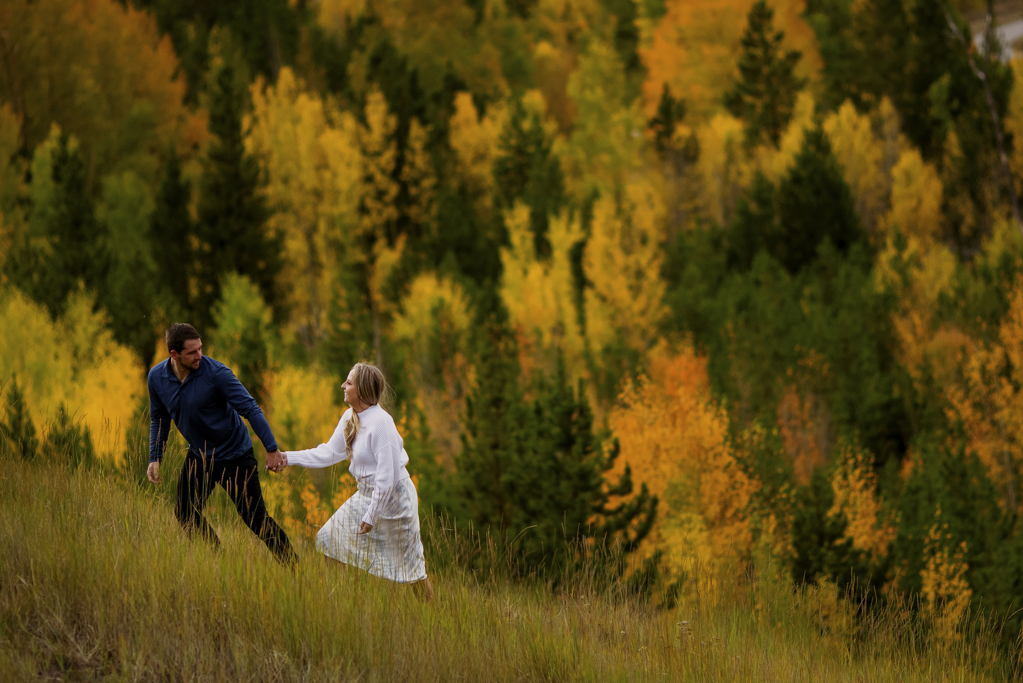 Chad guides Jamie up a steep slope during their engagement photos in Frisco, Colorado
