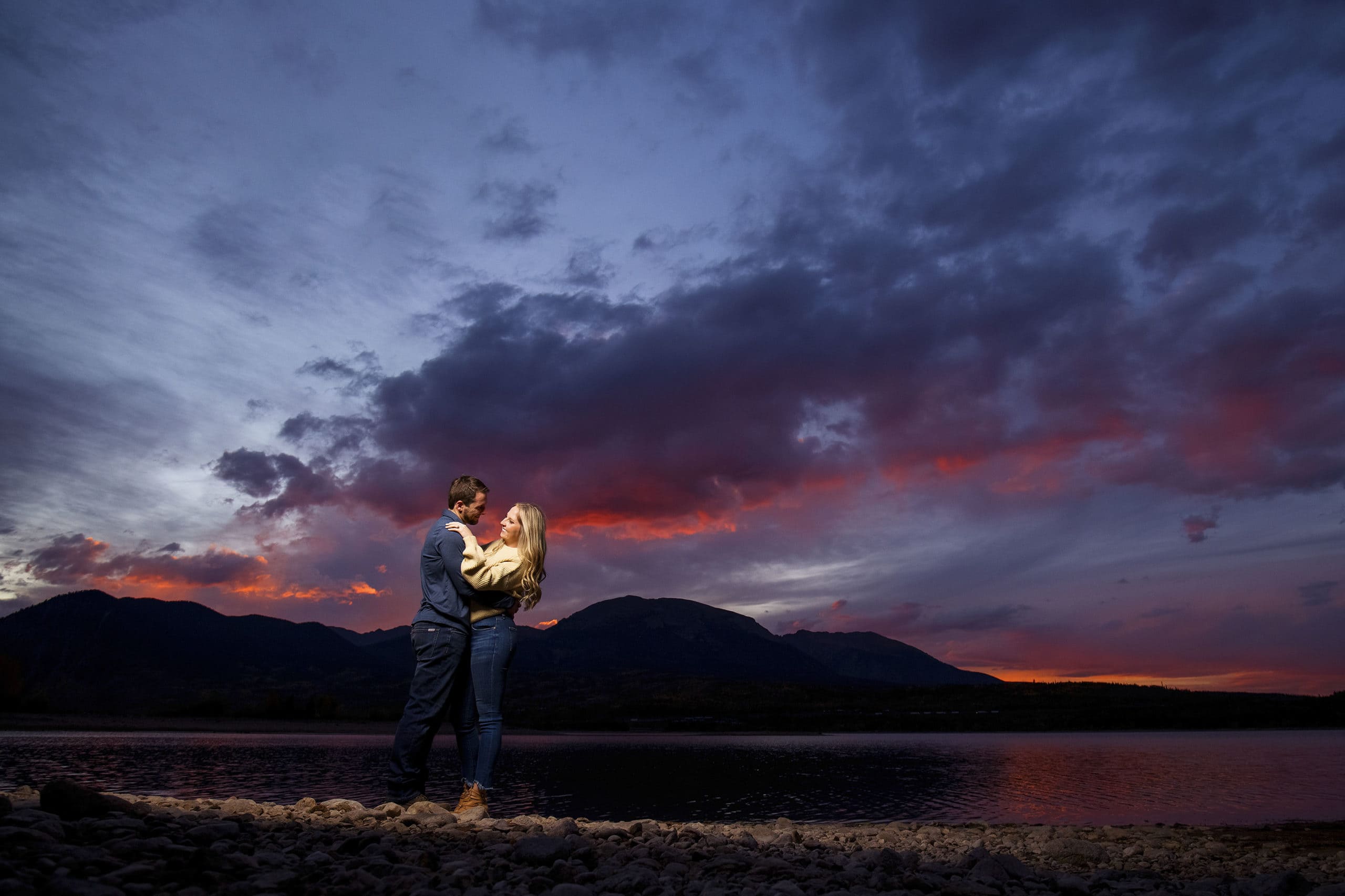 Chad embraces Jamie near the edge of Dillon Reservoir at sunset during their engagement photos