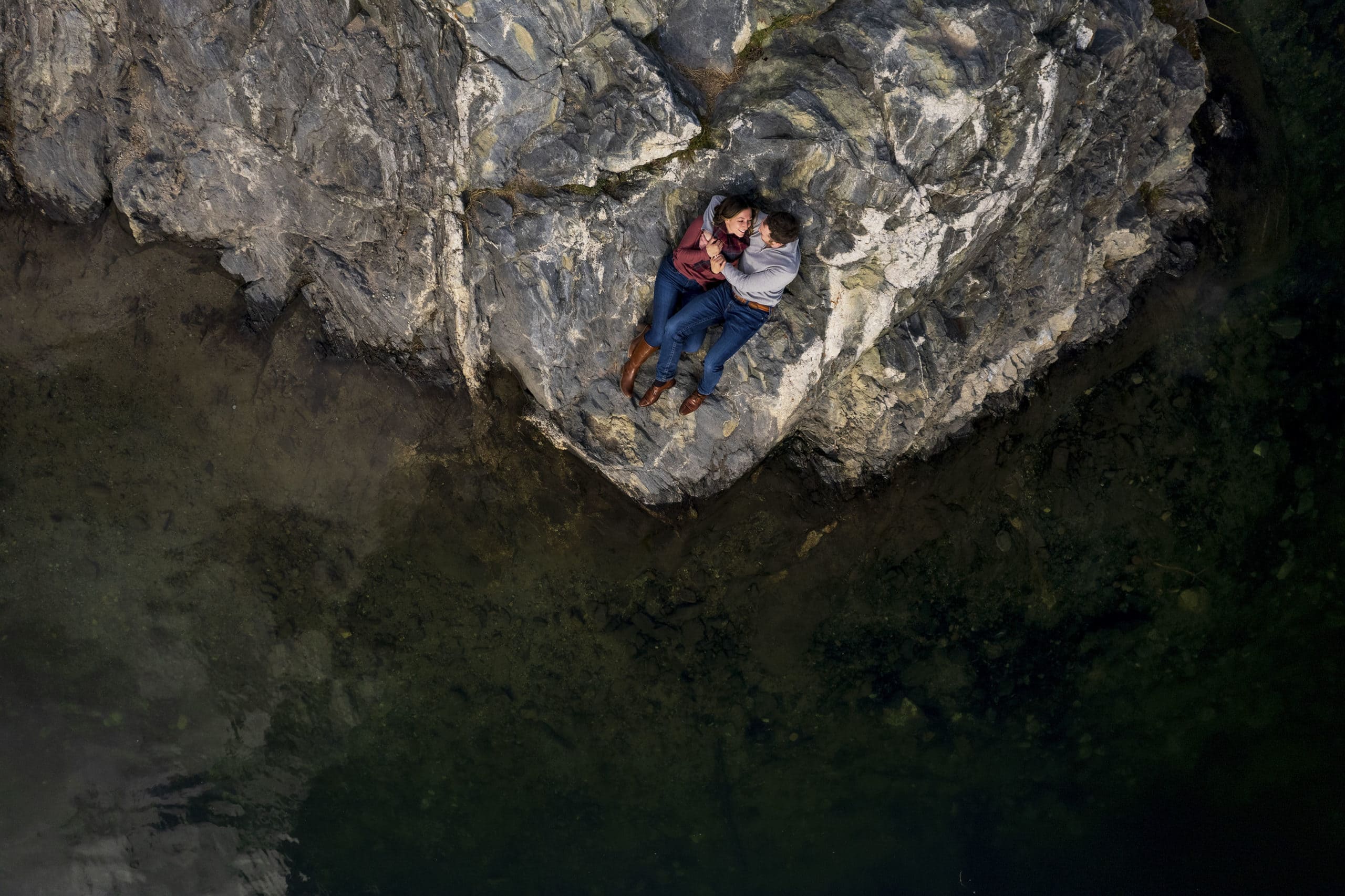 An arial photo shows a couple embracing on a rock pinensula at Officers Gulch in Frisco, Colorado