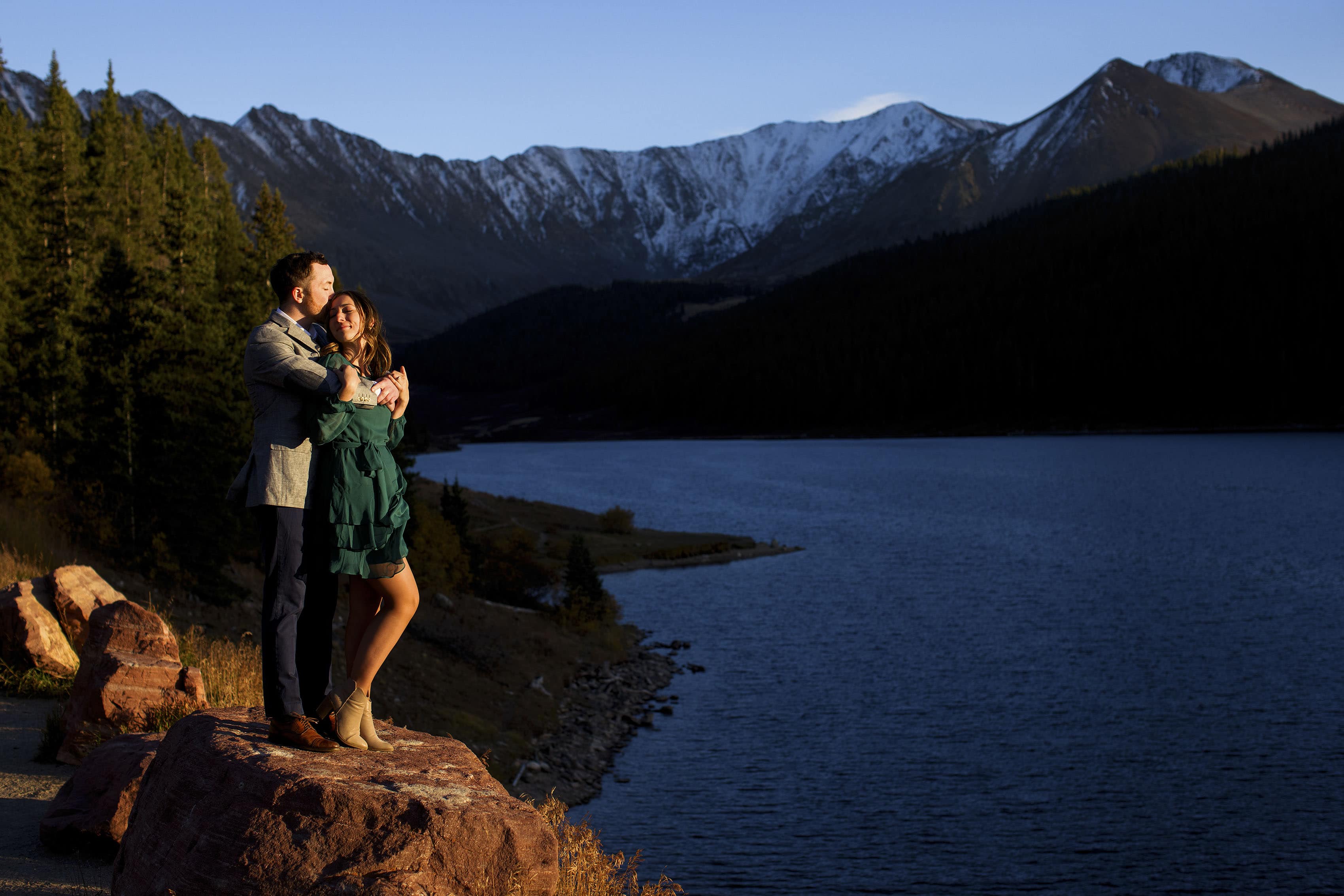 Gavin kisses Caitlin as they stand on a rock during their engagement photos at Clinton Gulch Dam Reservoir