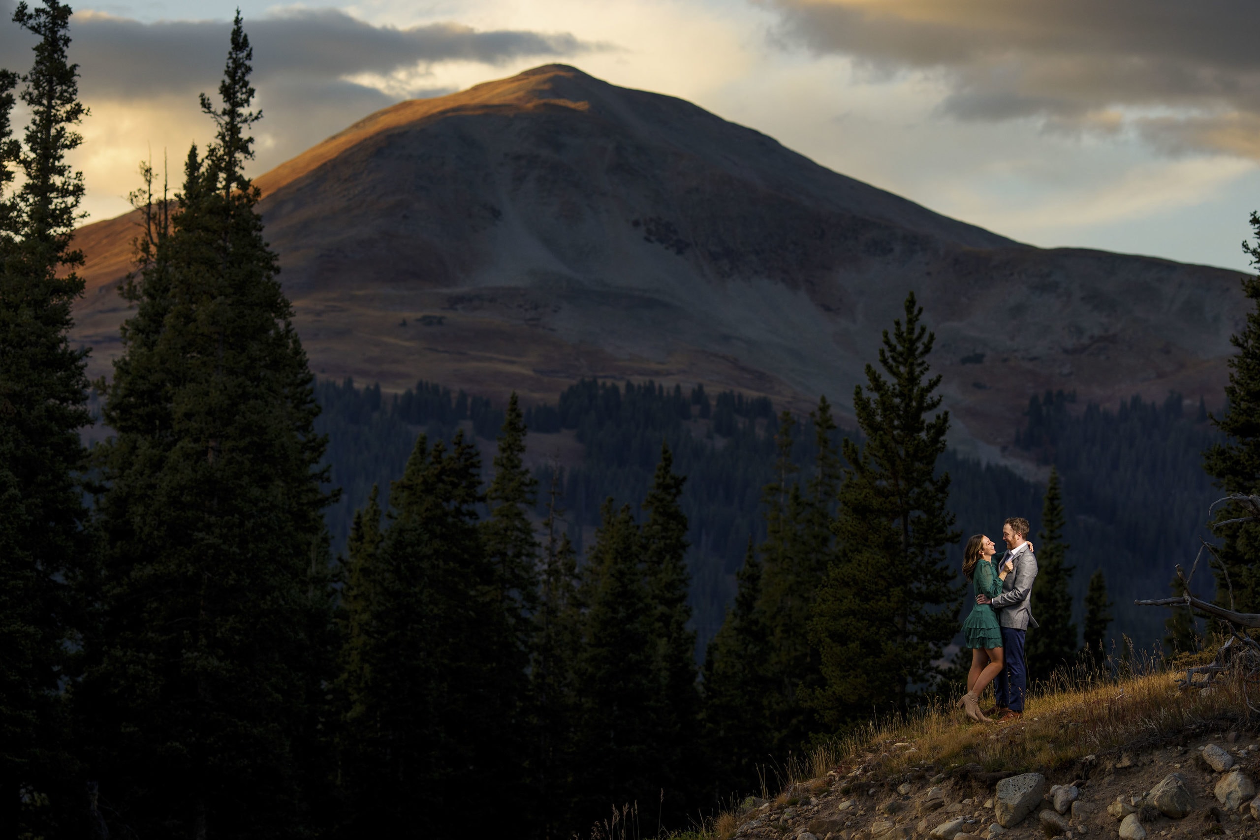 The sun sets over the mountain as a couple poses on a ridge near Leadville, Colorado