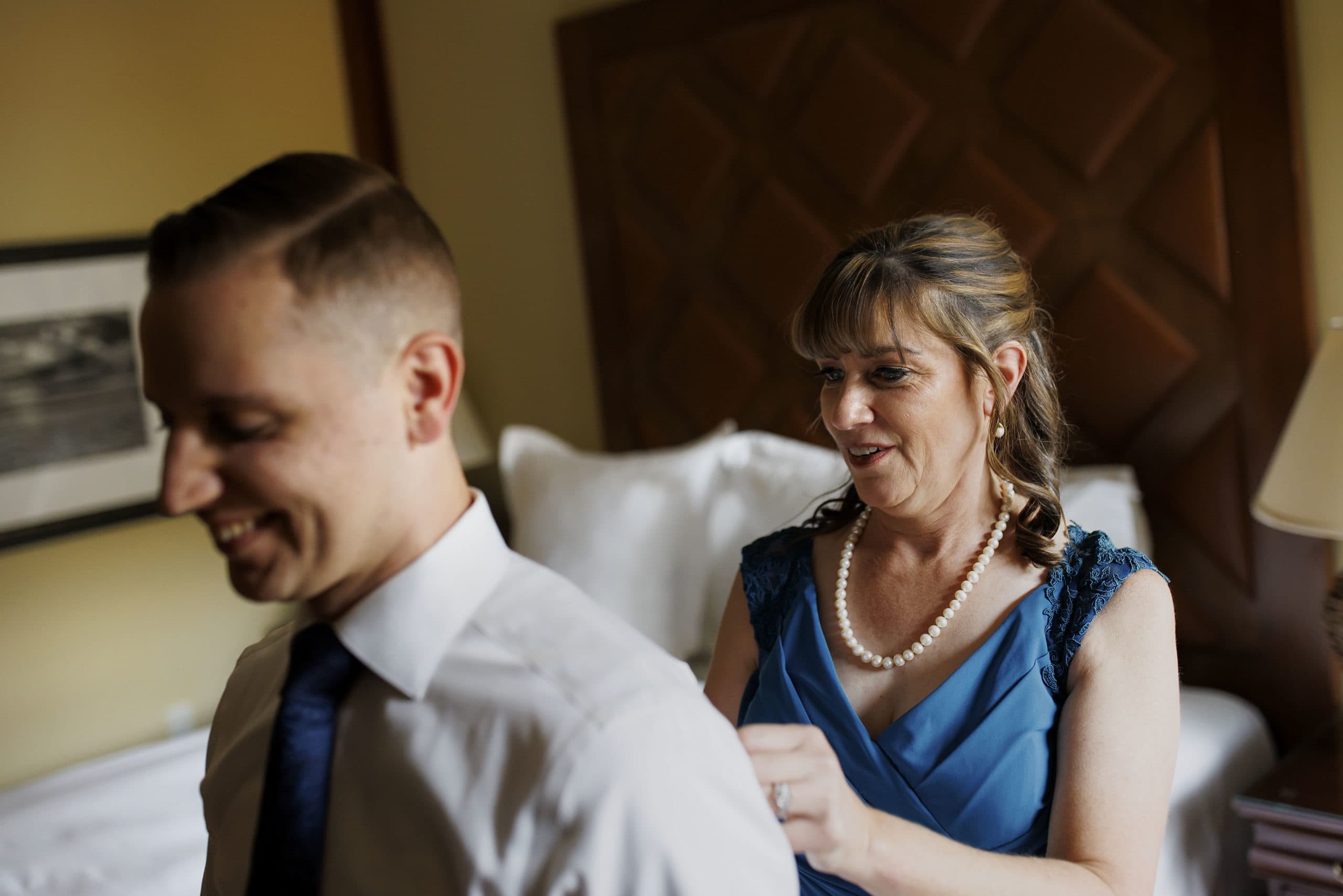 The groom’s mother helps him get dressed