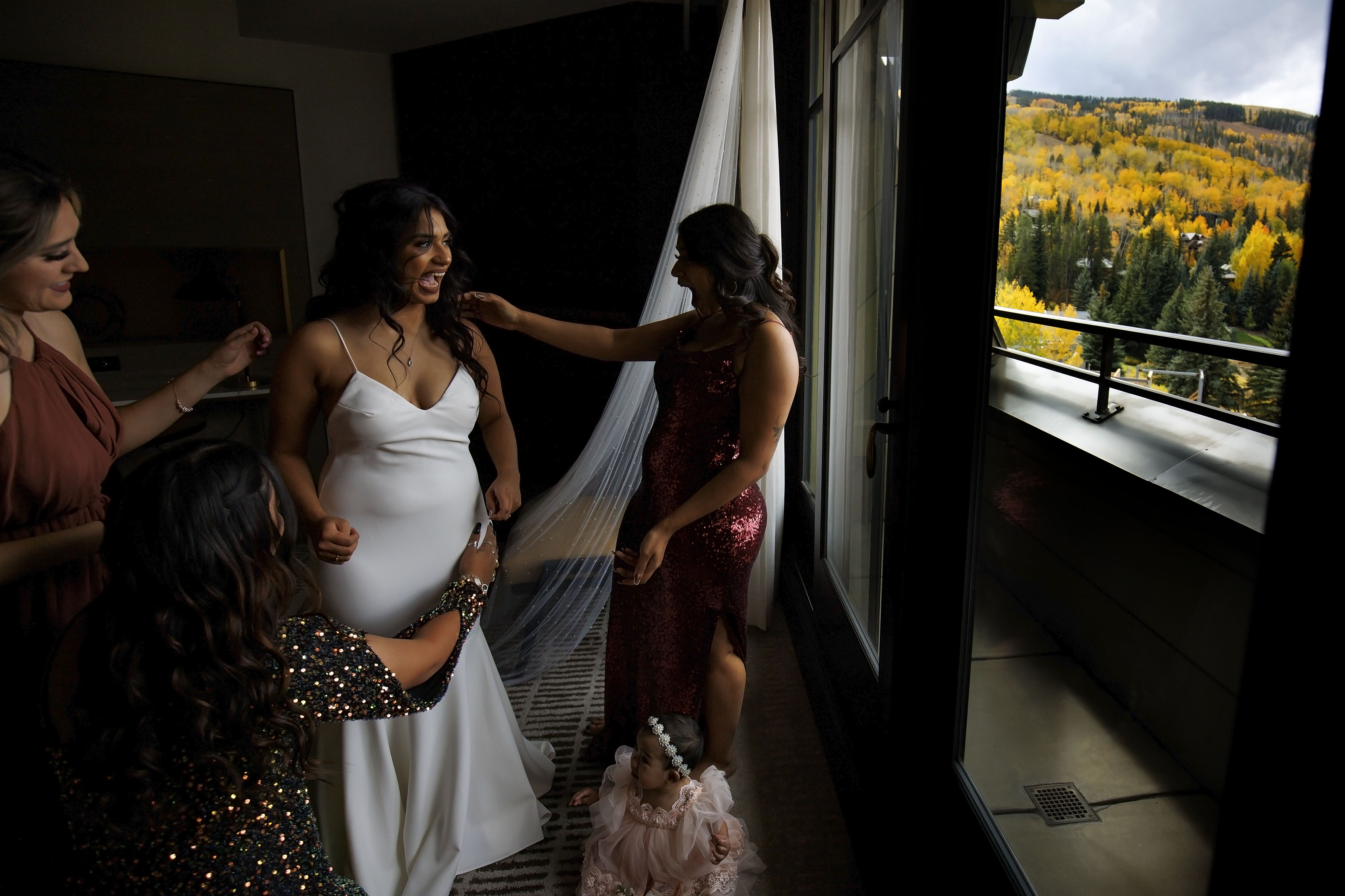 The Bride laughs with her sister while getting into her wedding dress at Four Seasons Resort and Residences Vail