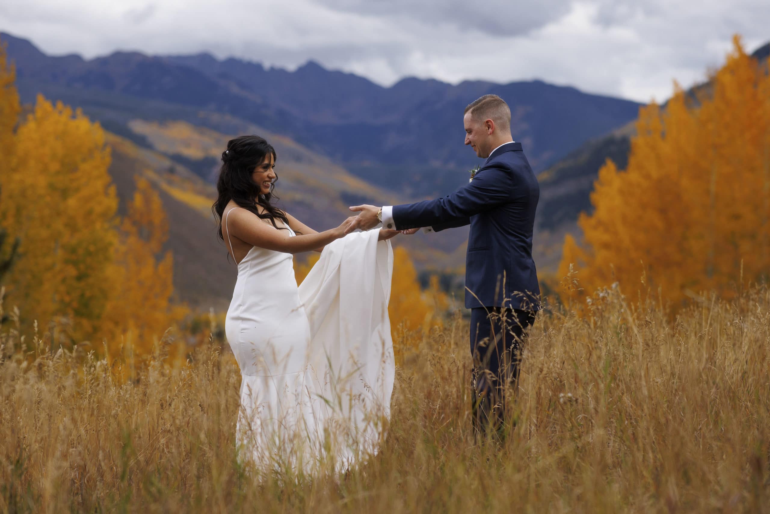 The bride and groom react during their first look in Vail surrounded by fall colors and the Gore Range on their wedding day