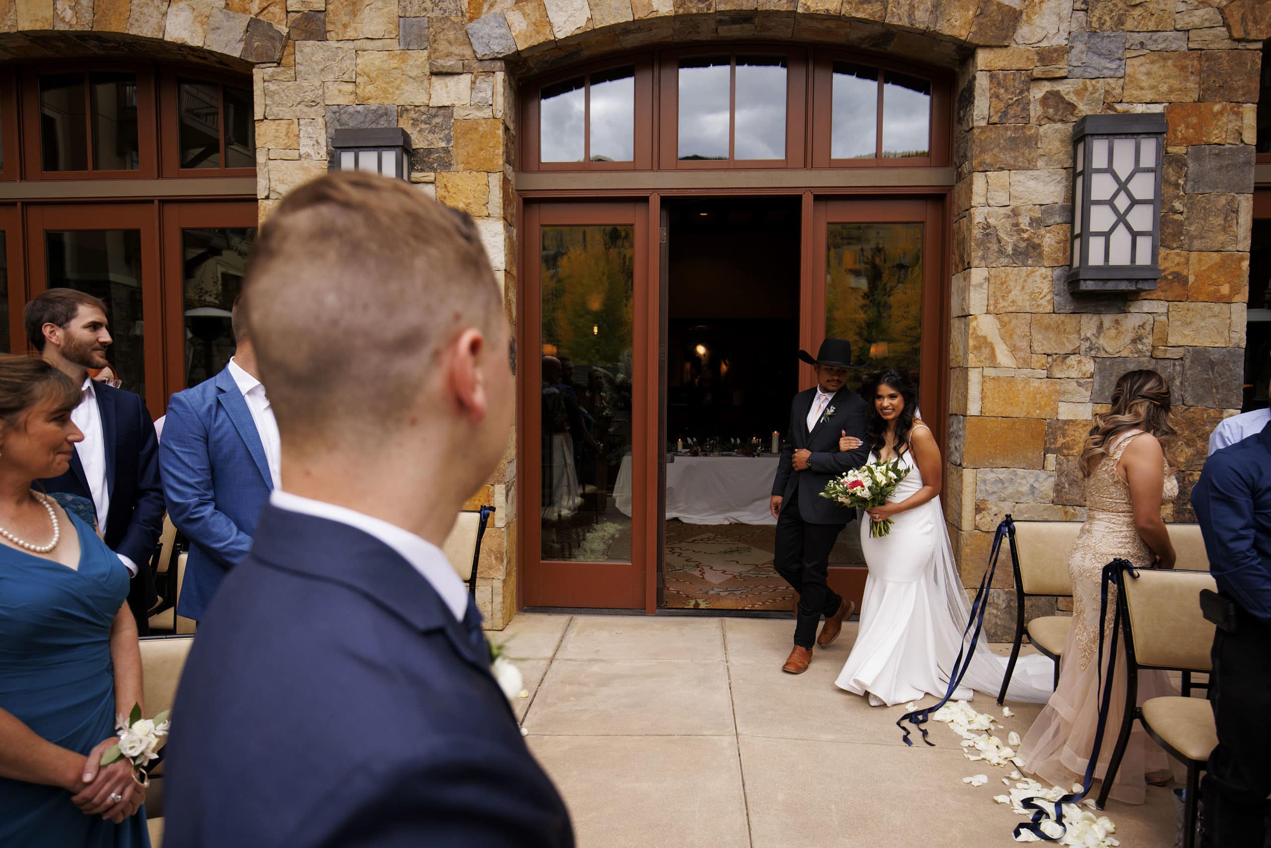 The bride is escorted by her brother down the aisle at Four Seasons Resort and Residences Vail during the wedding ceremony