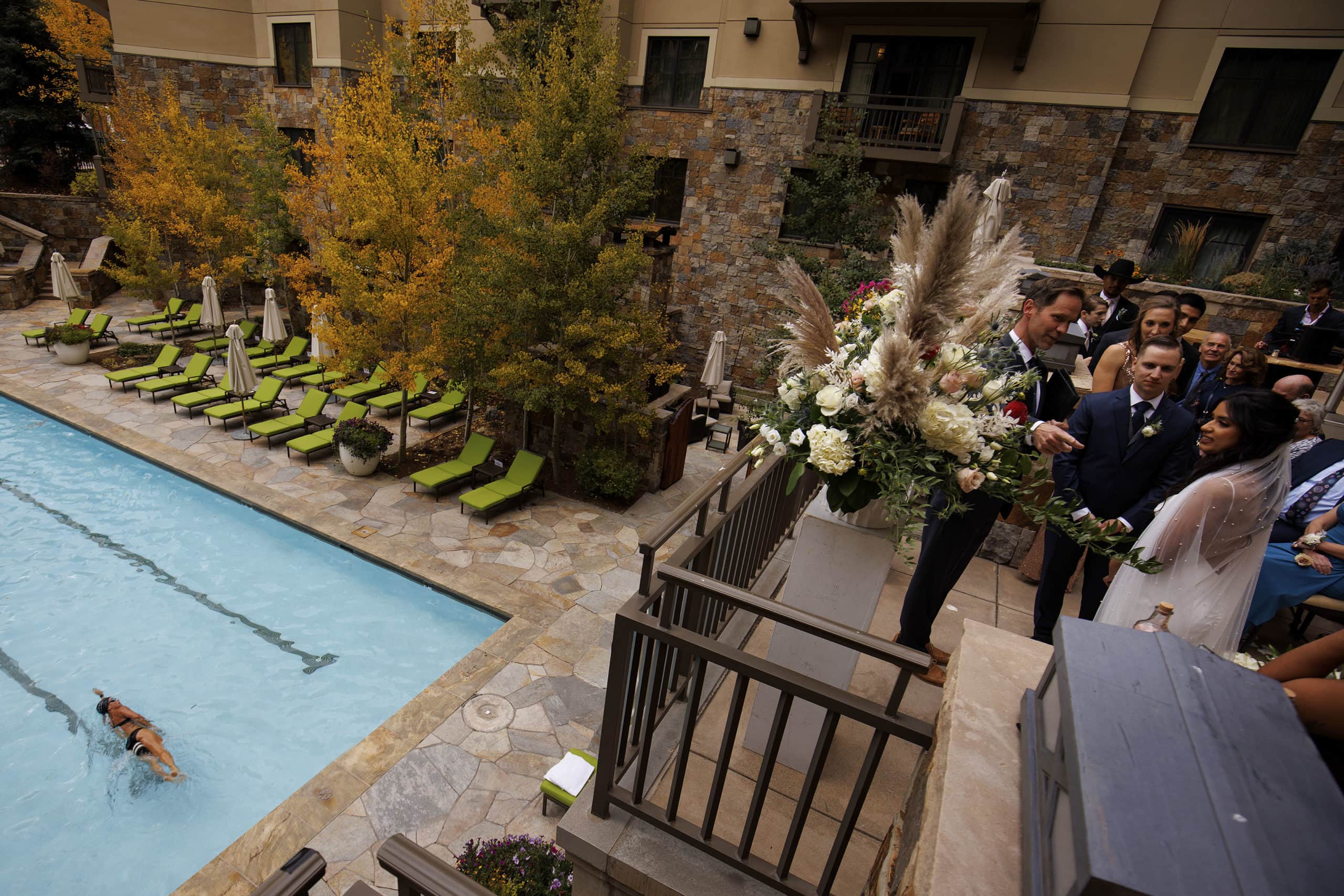 A hotel guest swims laps during Jennifer and Jon’s wedding ceremony at Four Seasons Resort and Residences Vail