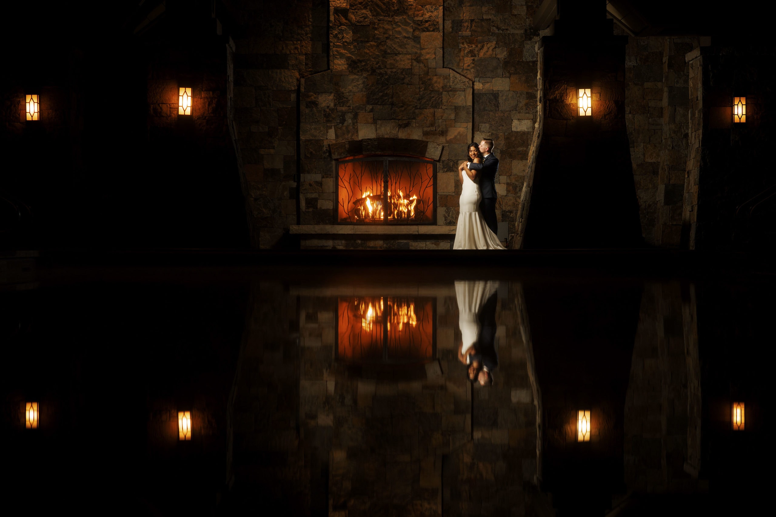 The bride and groom pose in front of the fireplace on their wedding day at Four Seasons Resort and Residences Vail