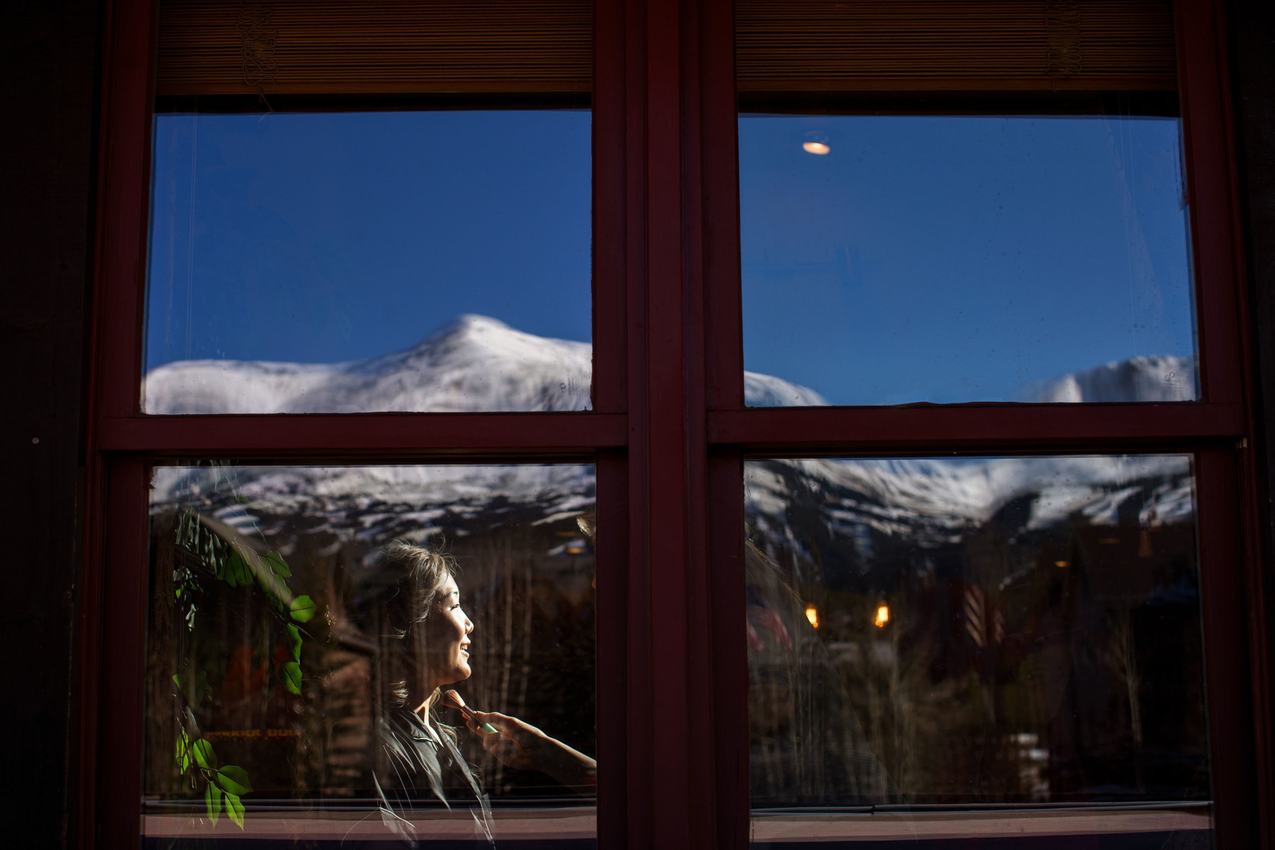 Julia gets her makeup done as Breckenridge mountain is reflected in the window