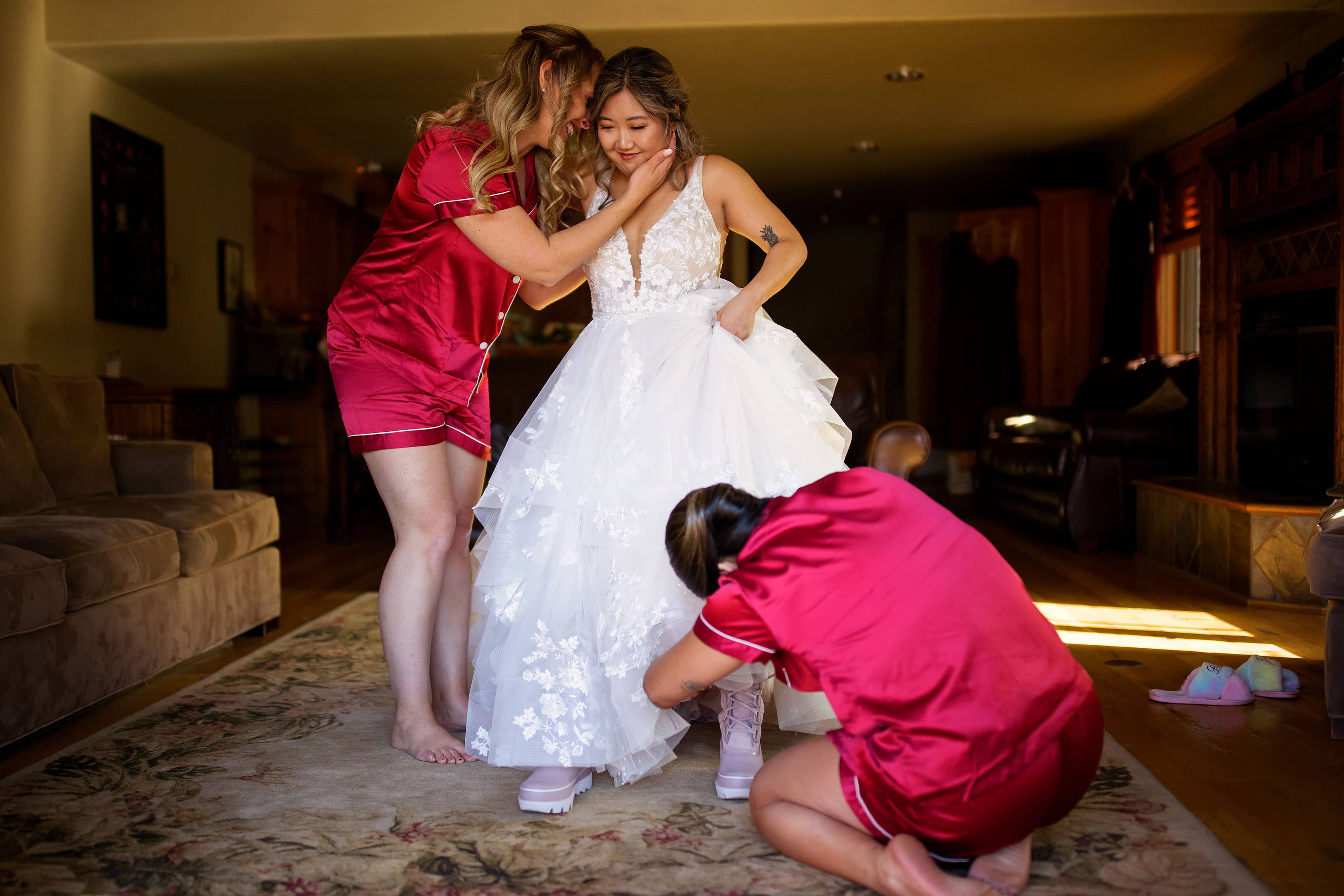 The bride gets help getting into her dress