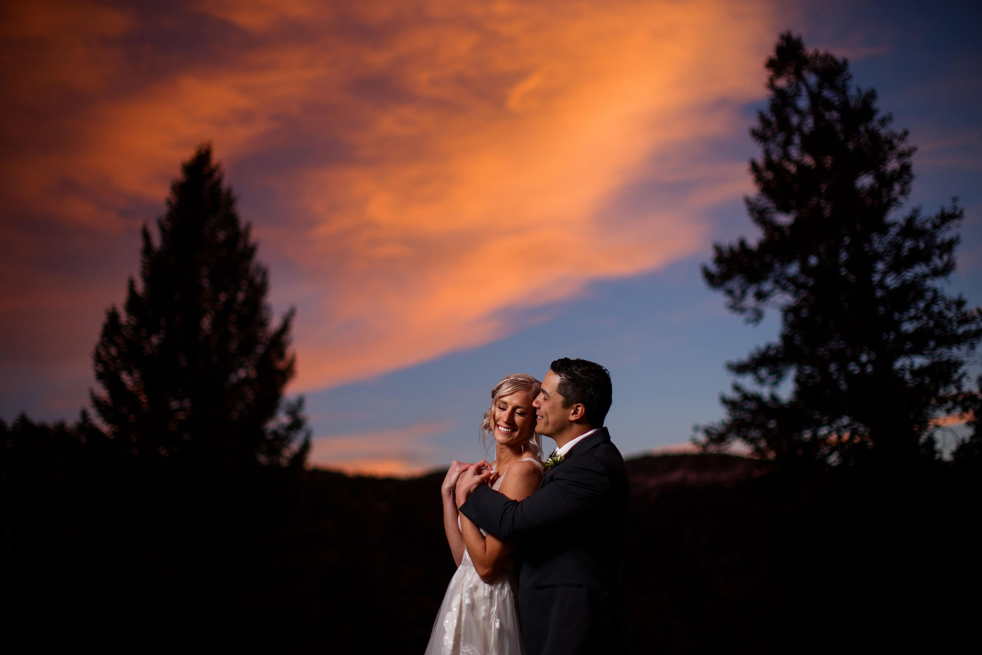 Lindsey and Josh embrace during sunset at Woodlands wedding venue in Morrison, CO