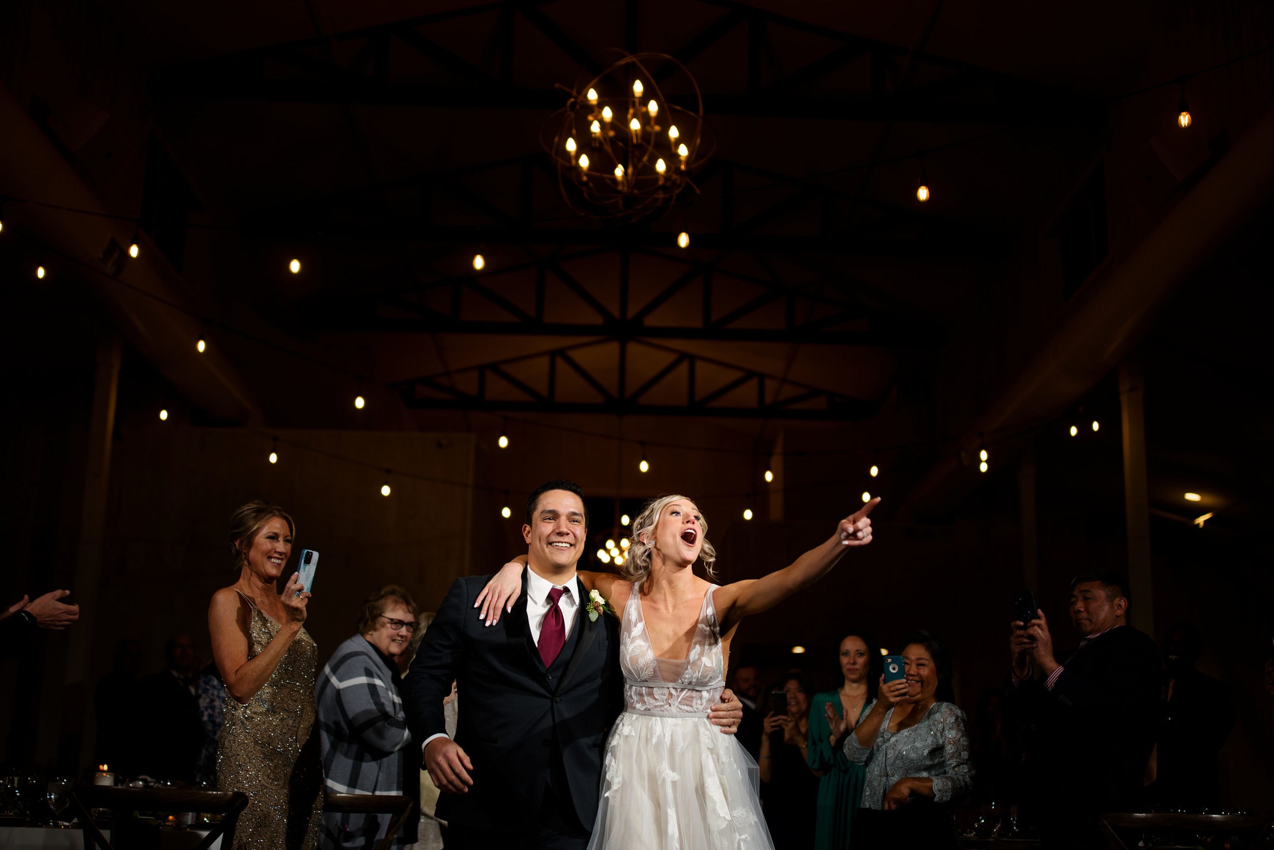 The bride and groom react during their grand entrance at Woodlands in Morrison, Colorado
