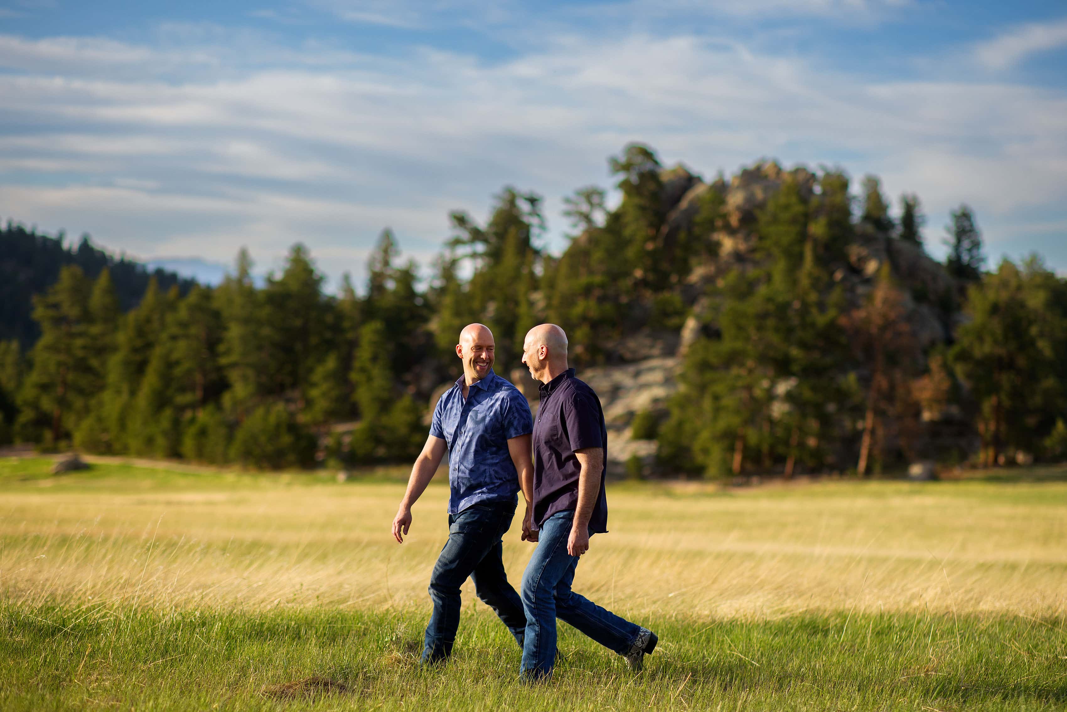 Josh and Todd walk in the meadow at Alderfer Three Sisters Park in Evergreen during their engagement