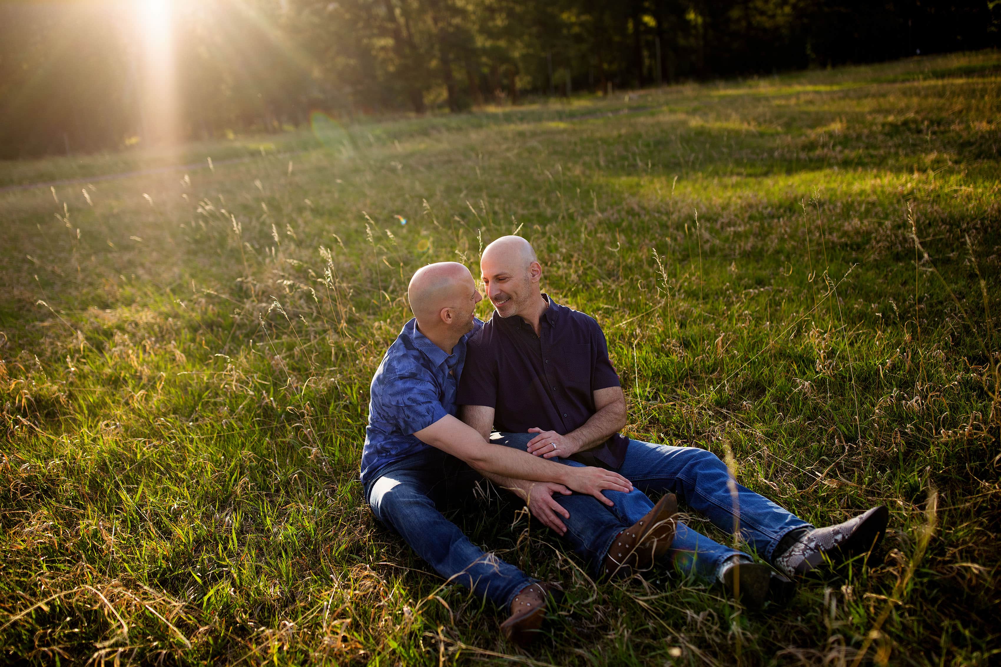 A couple sits in the meadow during their Evergreen engagement