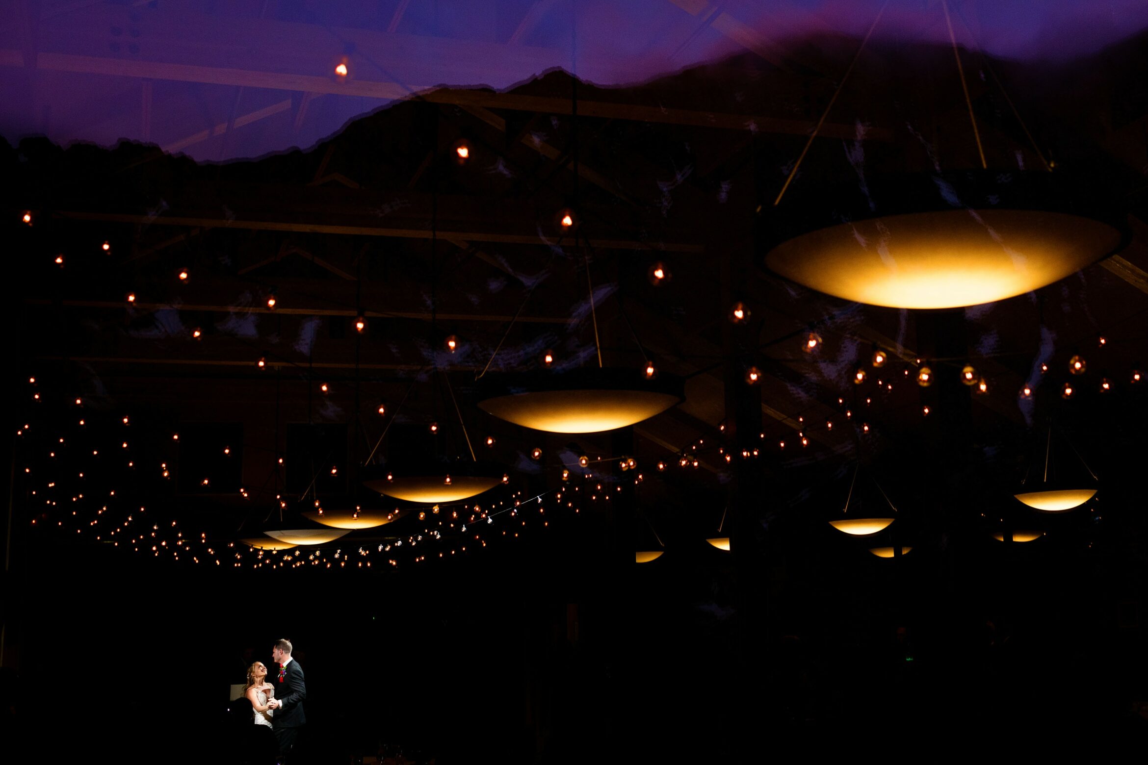Diana and Eric share their first dance as the sun set is reflected in the window at Black Mountain Lodge