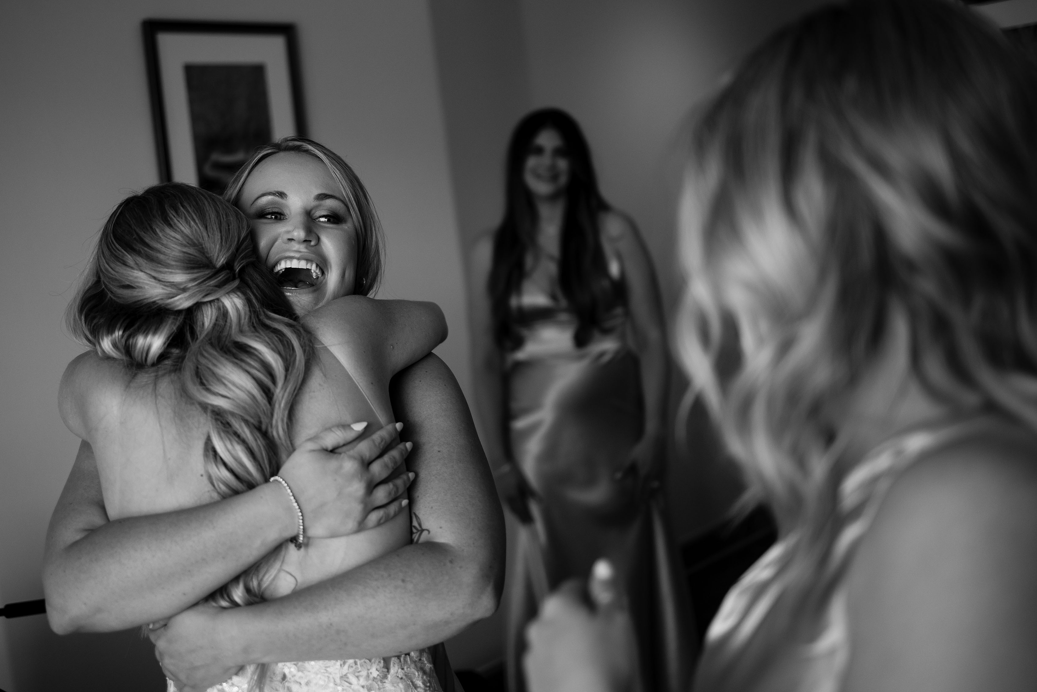 Bridesmaid laughs and hugs the bride