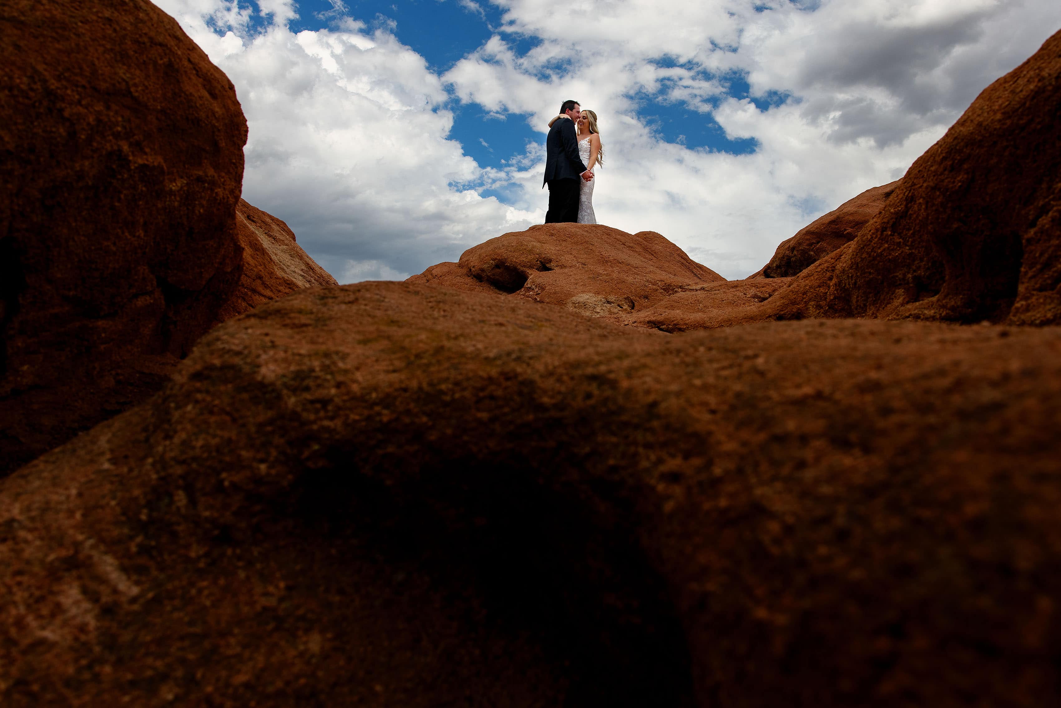 Jamie and Chad pose together on a red rock formation at Garden of the Gods park in Colorado Springs on their wedding day