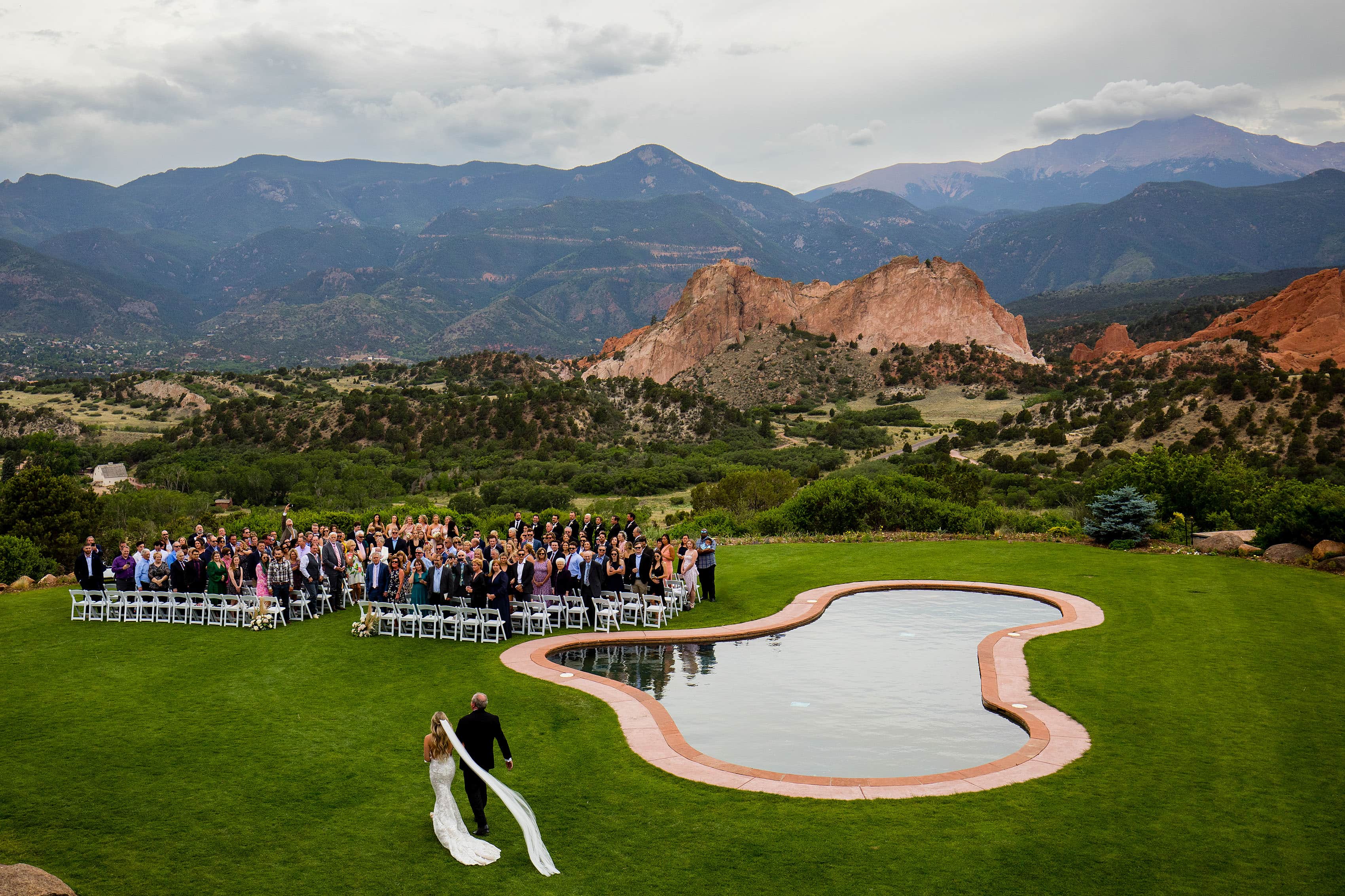 The bride and her father walk on the lawn during the wedding ceremony at Garden of the Gods Resort in Colorado Springs