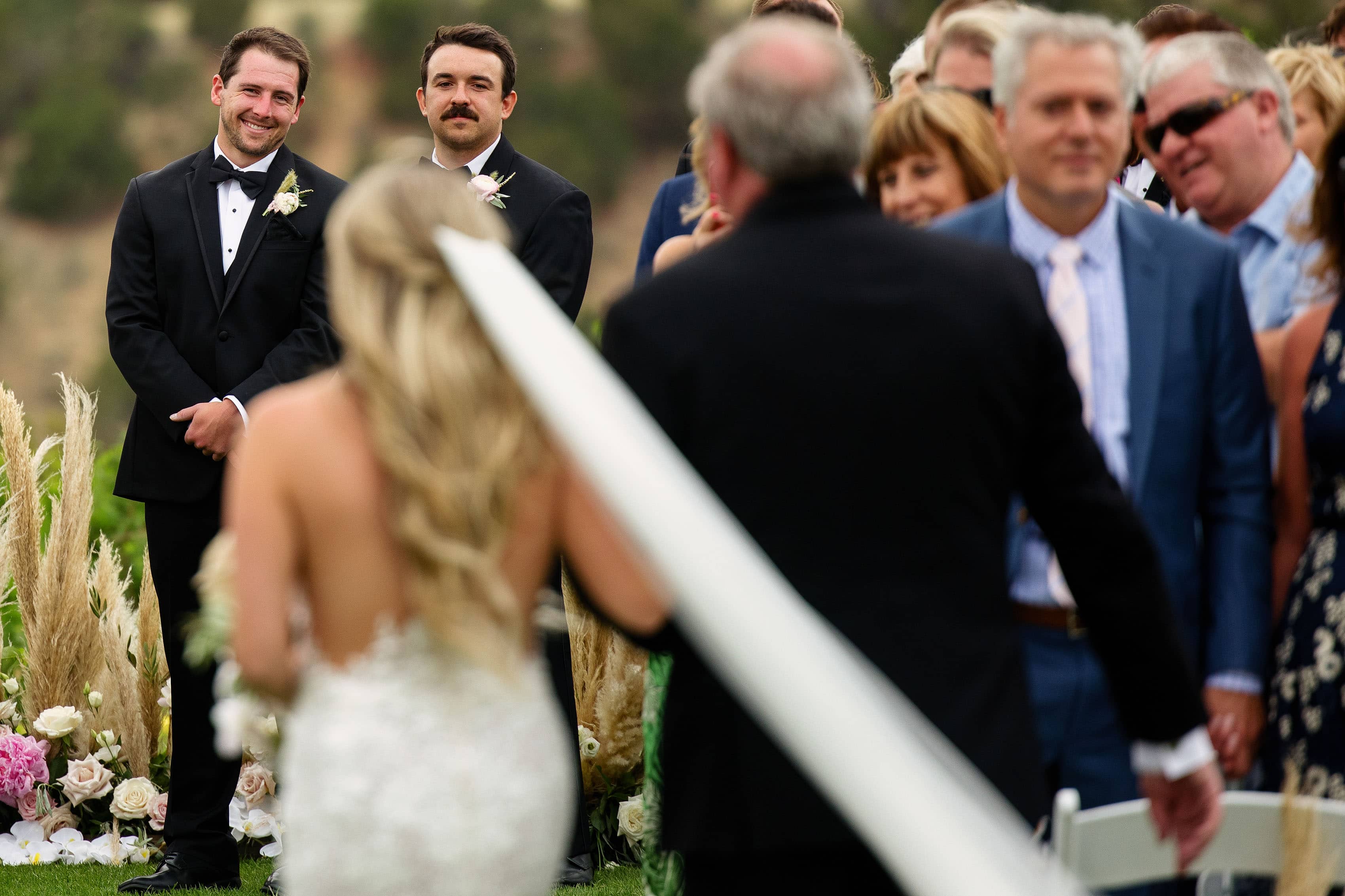 The grooms smiles as the bride walks down the aisle