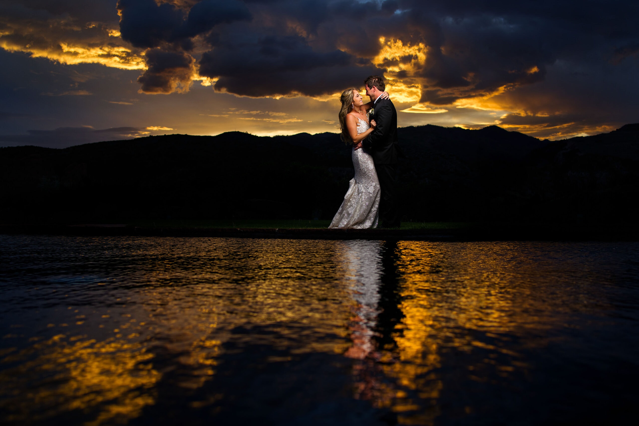 The newlyweds pose for a photo near the reflection pool as the the sun sets behind the mountains at Garden of the Gods Resort