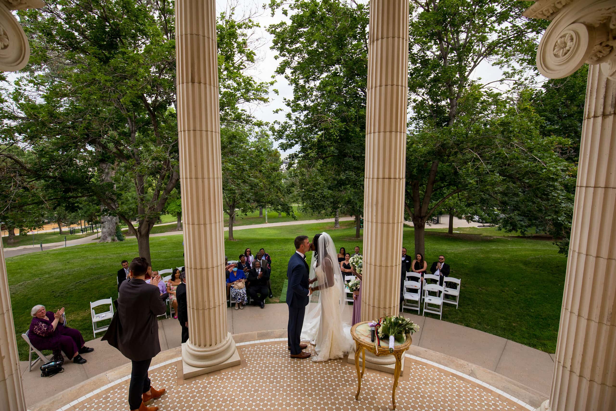 The bride and groom share their first kiss during their wedding ceremony at Grant Humphrey’s Mansion in Denver