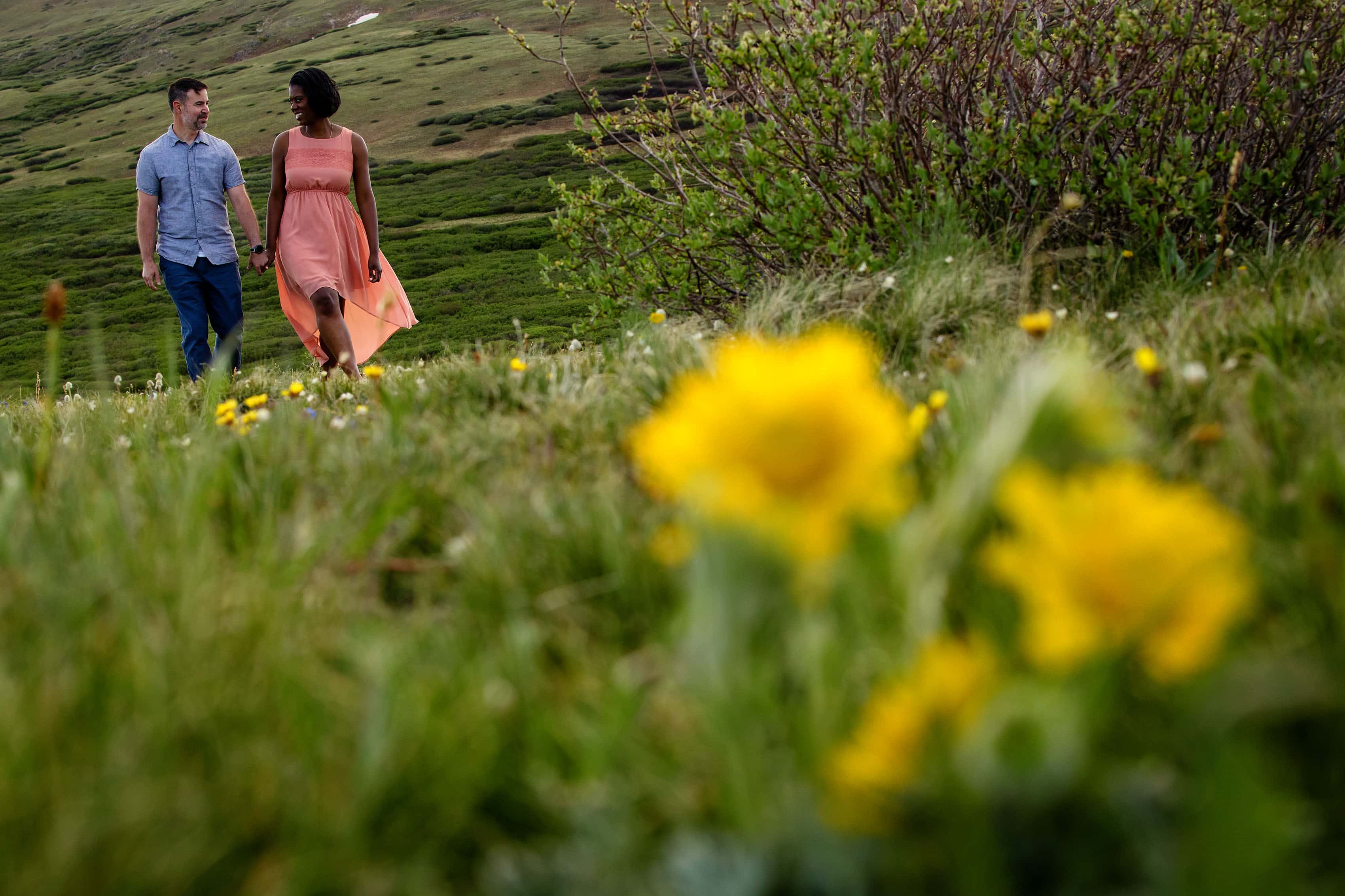 Aisha and Shad walk together near wildflowers in Colorado