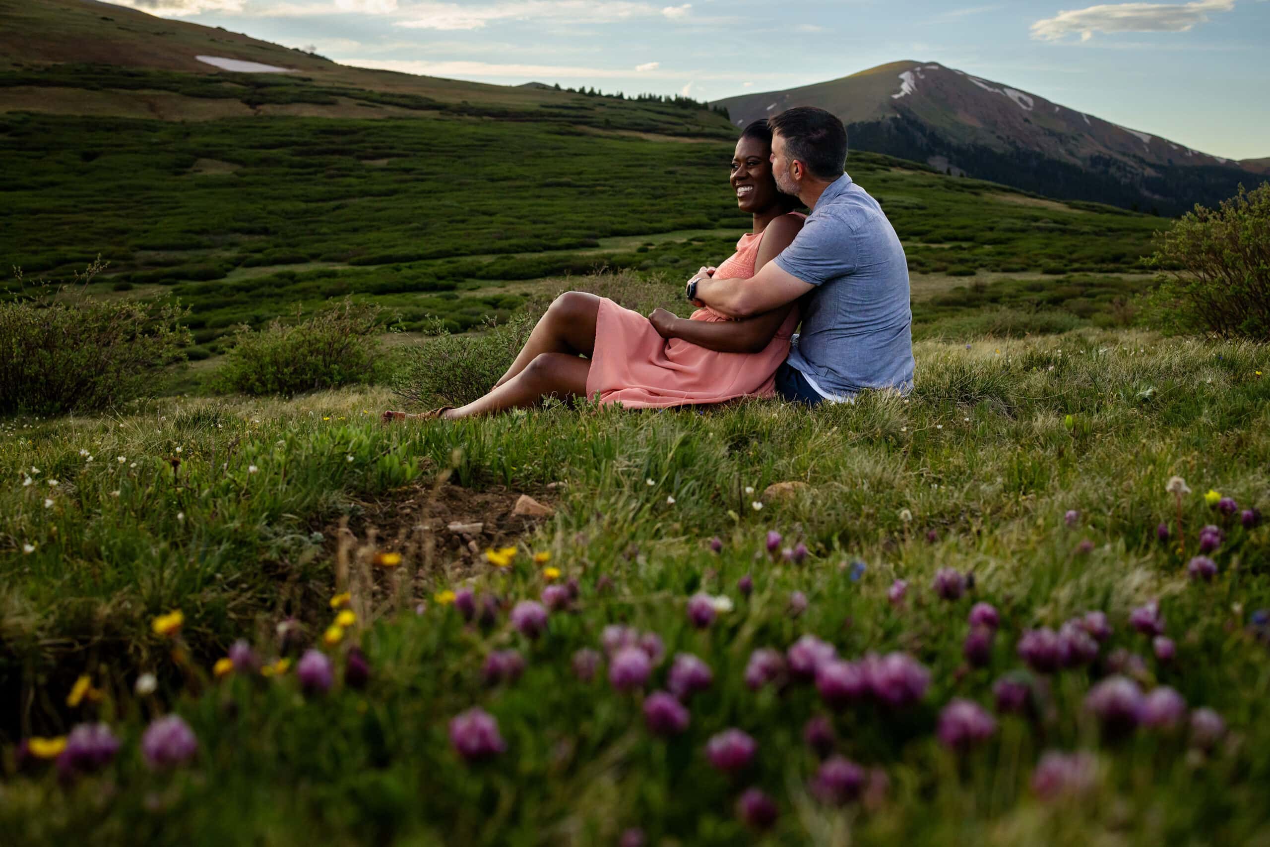 A couple sits near a grove of wildflowers on Guanella Pass during their engagement session