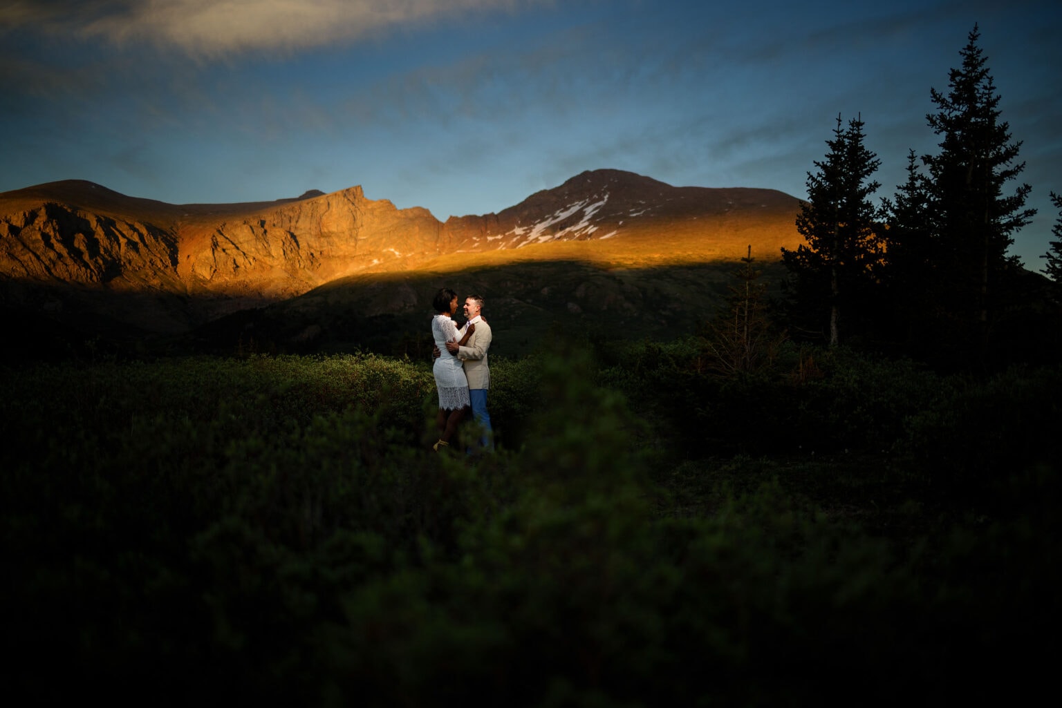 A couple poses together as alpenglow hits Mount Bierstadt during their engagement photos on Guanella Pass