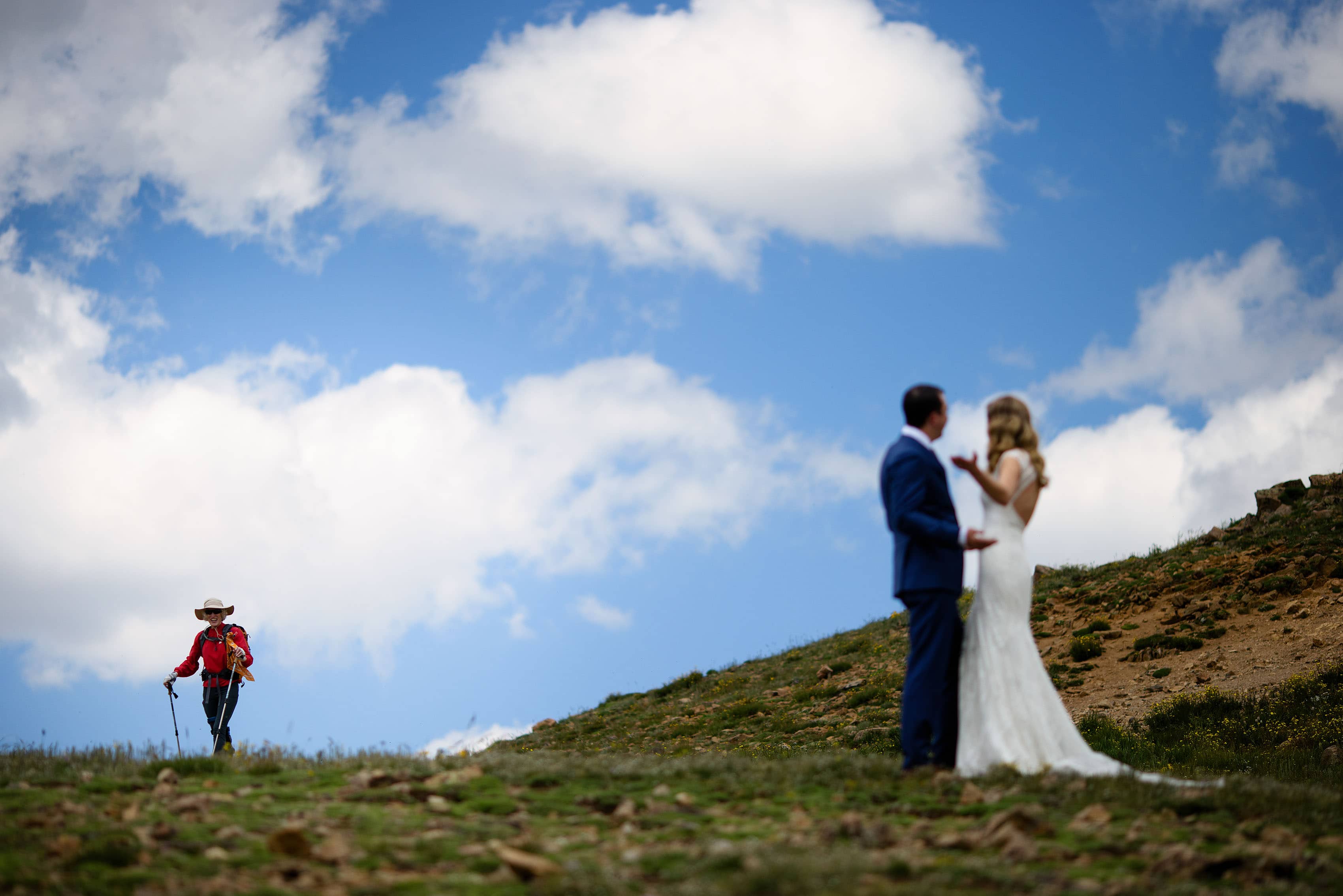The bride gestures towards a hiker on Loveland Pass
