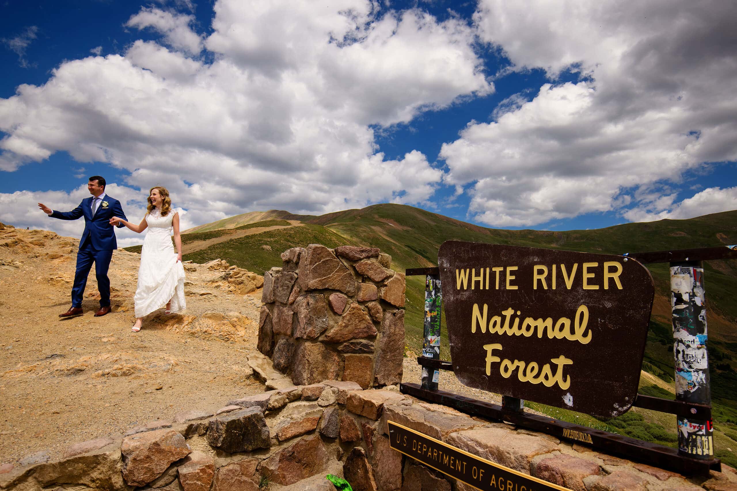 The bride and groom wave to onlookers atop Loveland Pass