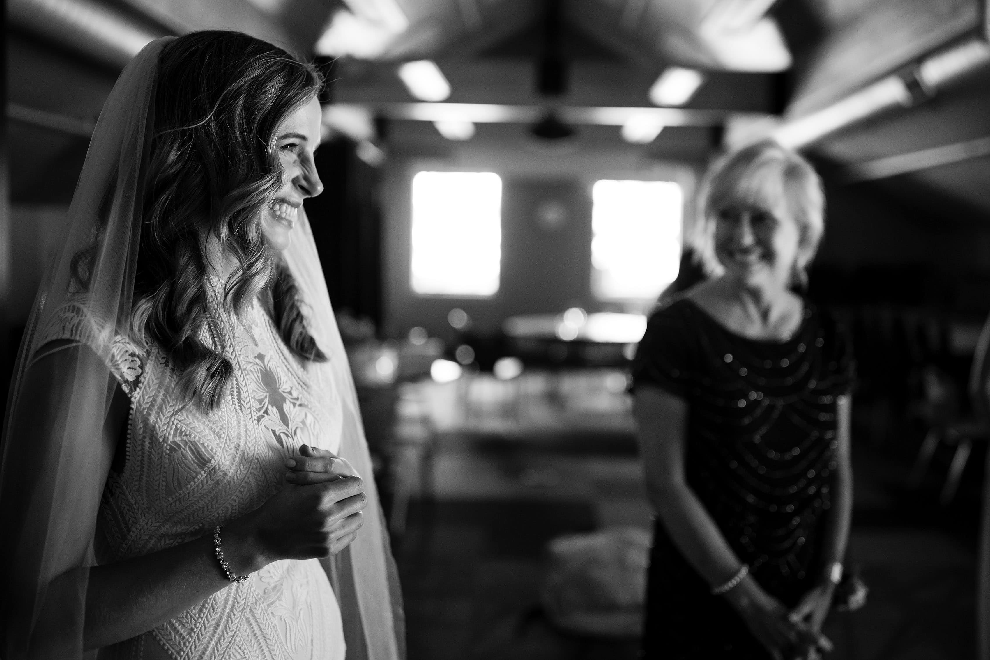 The bride smiles as her mother looks on