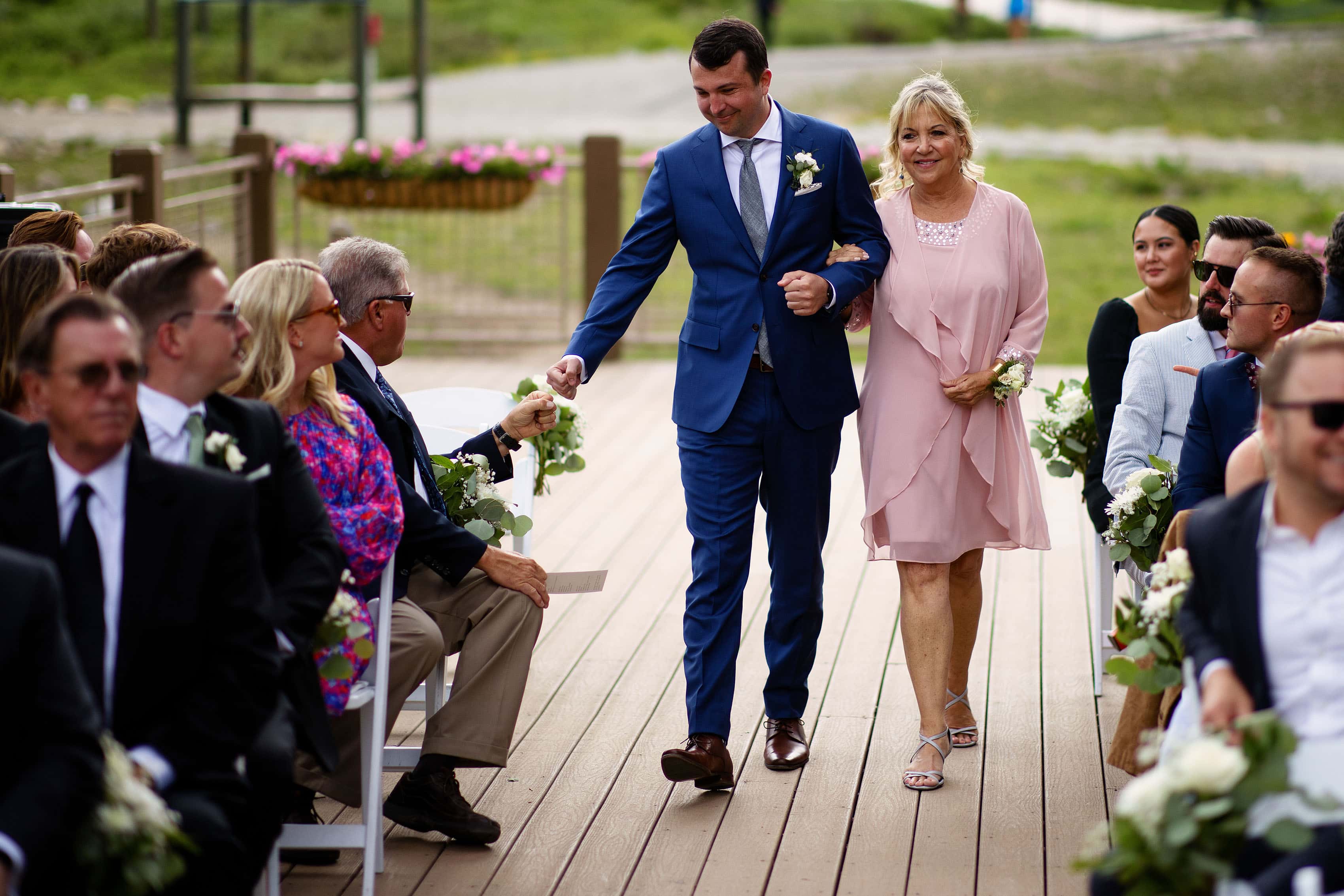 The groom gets a fist bump as he walks down the aisle with his mother