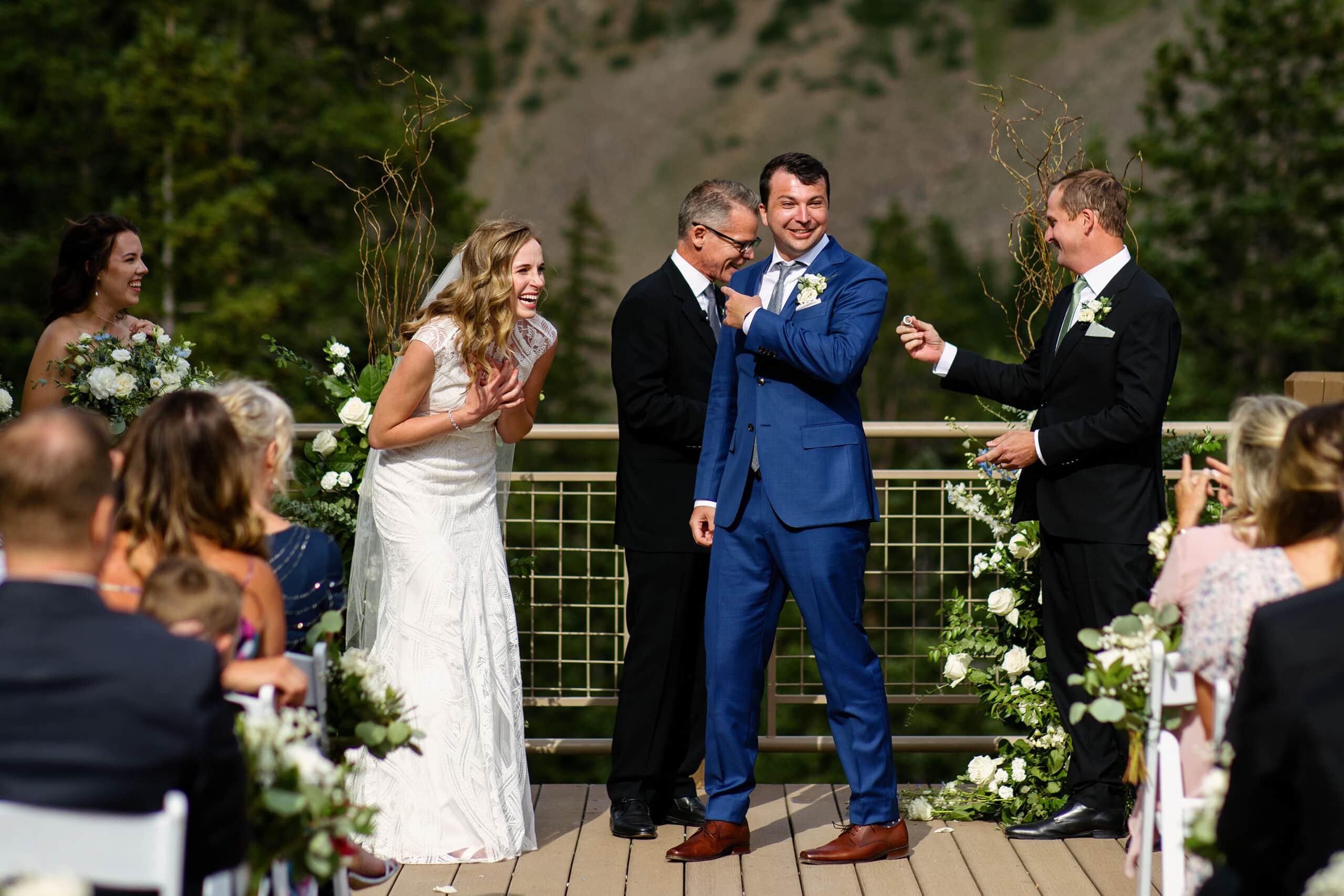 The bride and groom laugh as a groomsmen hands over the rings during their ceremony at Arapahoe Basin