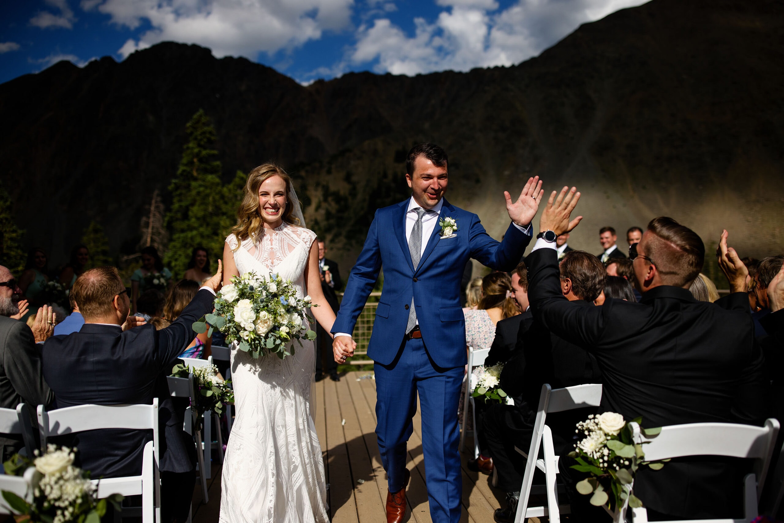 The groom gets a high five as he walks down the aisle with his bride after the ceremony at Black Mountain Lodge