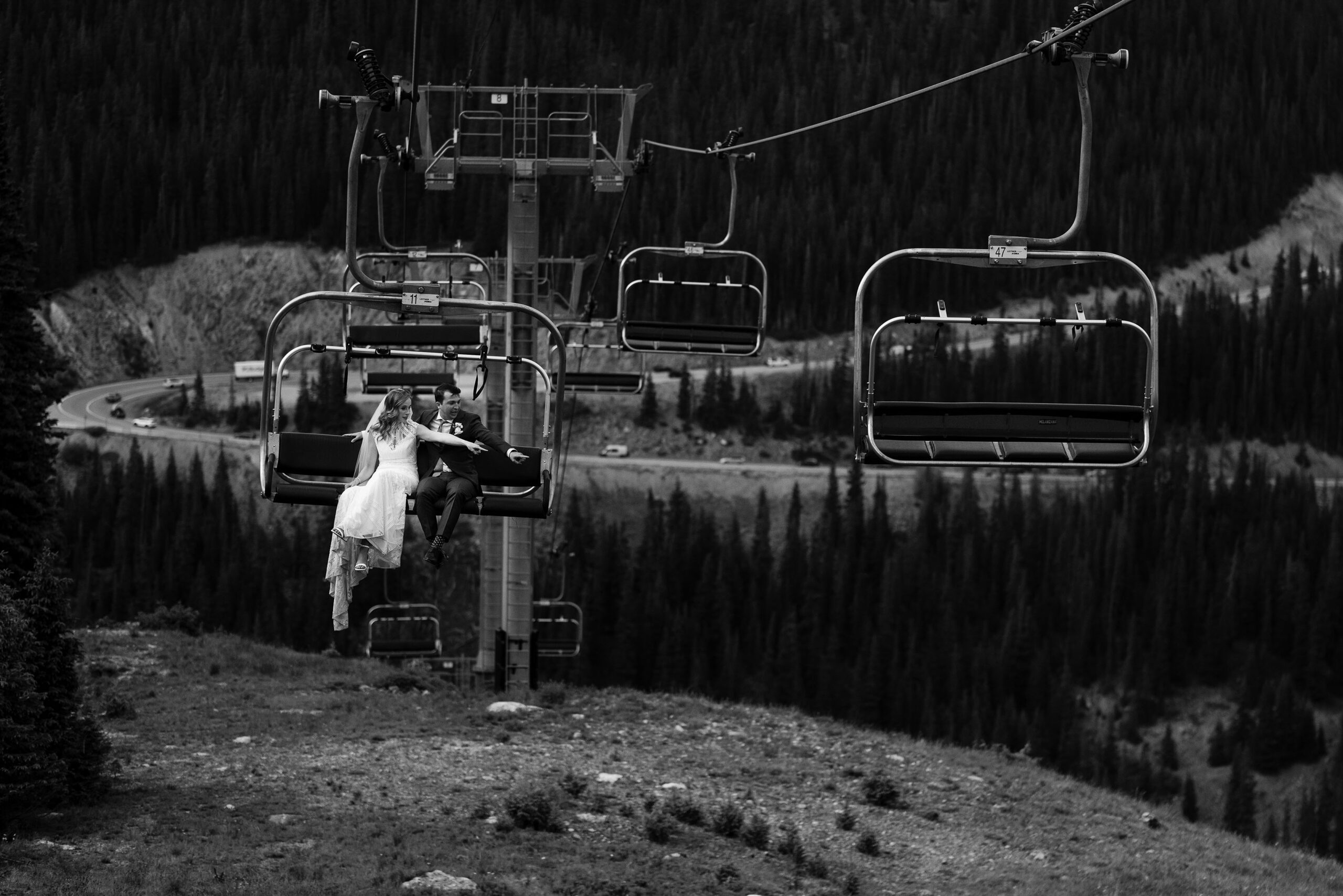 The bride and groom point to a deer while riding the chairlift