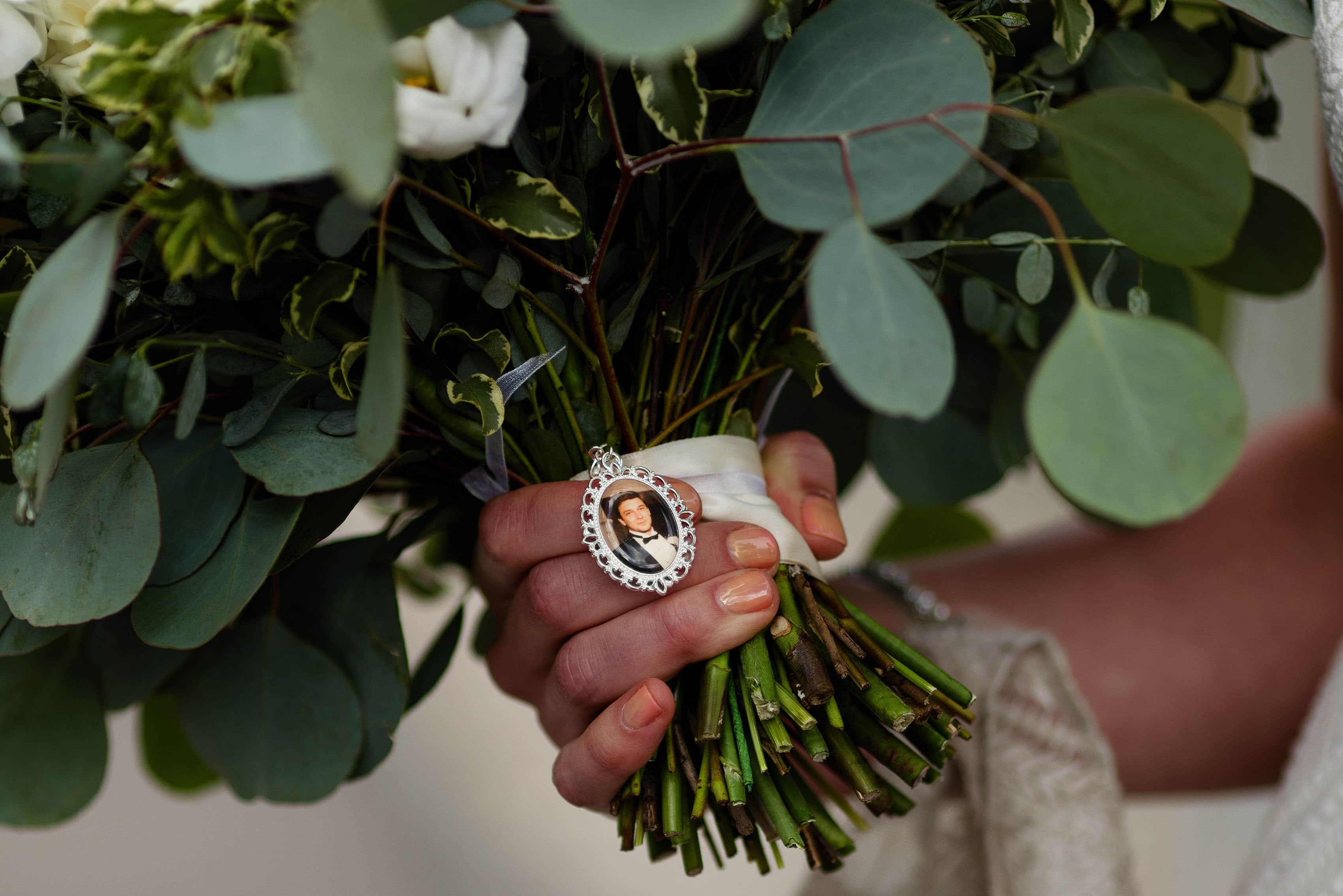 A detail of the bride’s father in a locket on her bouquet