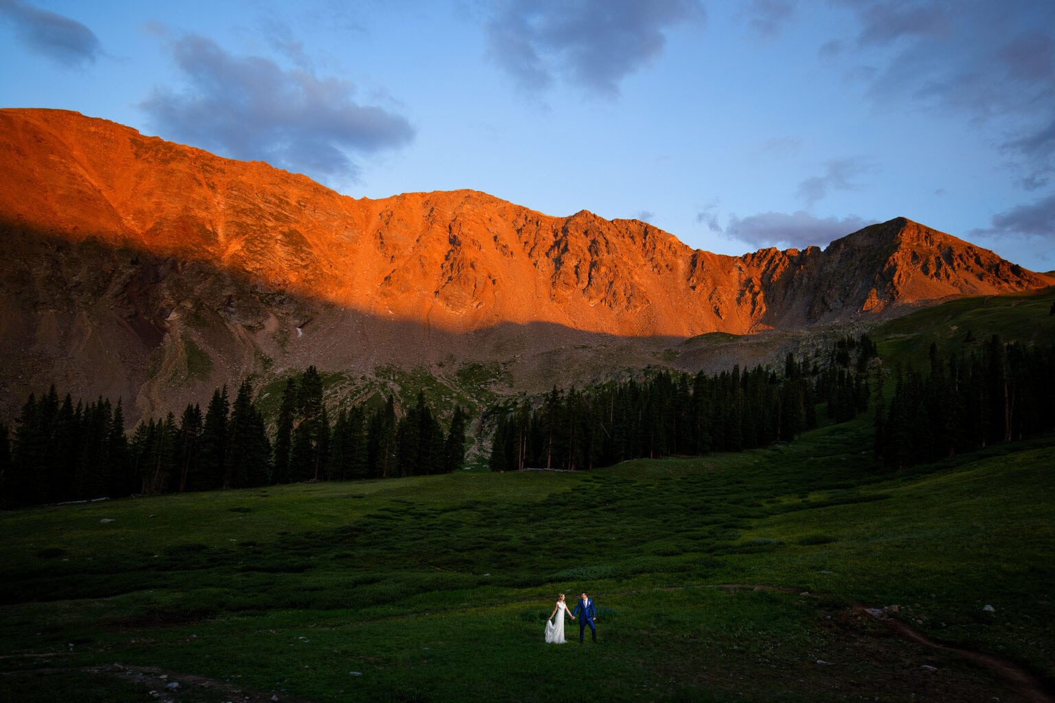 Keely and Steven pose as alpenglow illuminates the East Wall at Arapahoe Basin during their wedding day