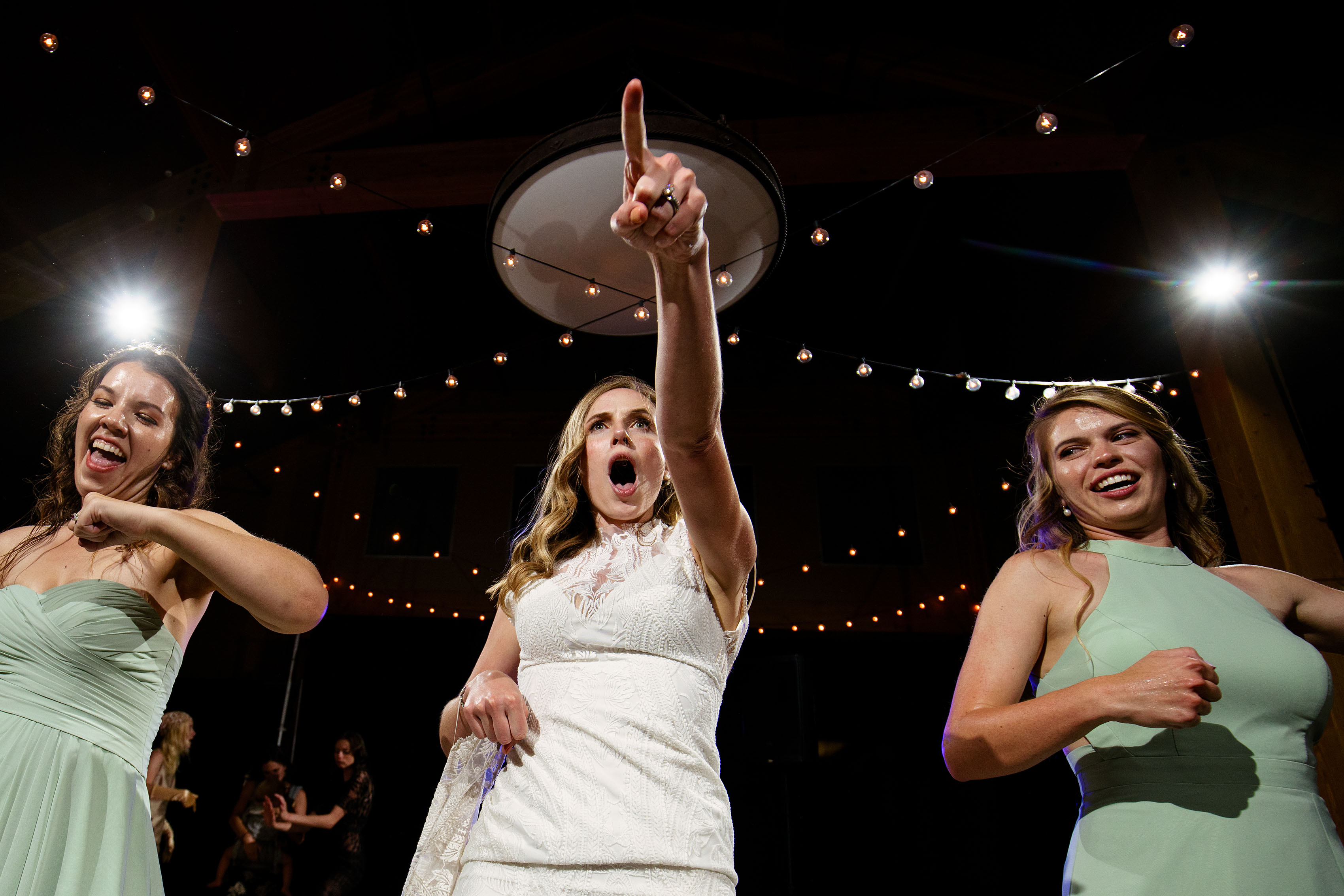 The bride points to a friend on the dance floor