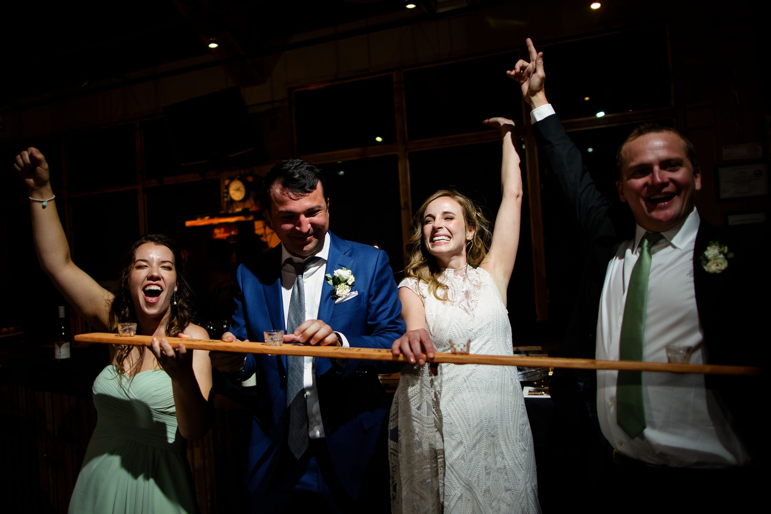 The bride, groom and friends react after taking a shot of liquor on a shotski