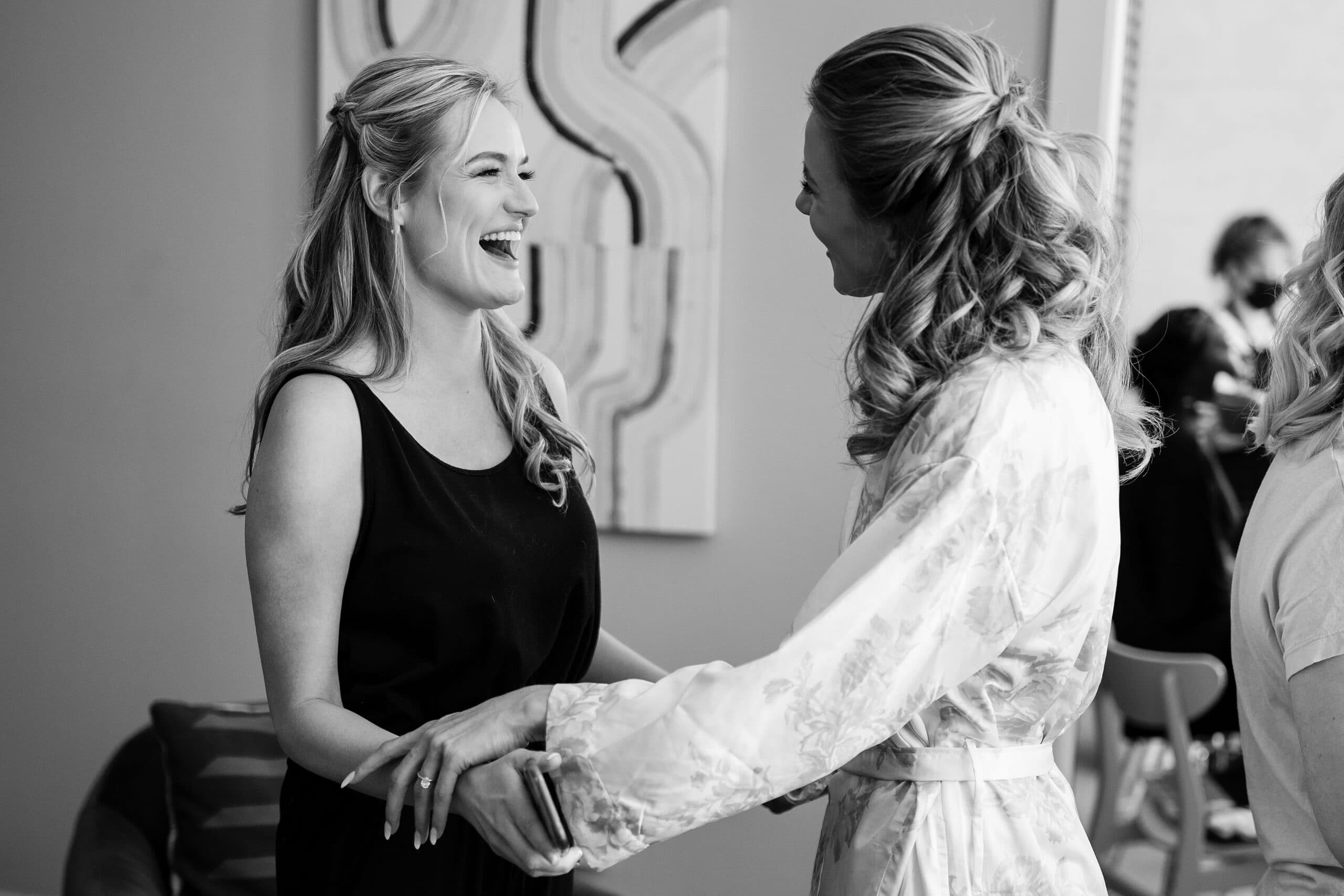The bride laughs with a bridesmaid