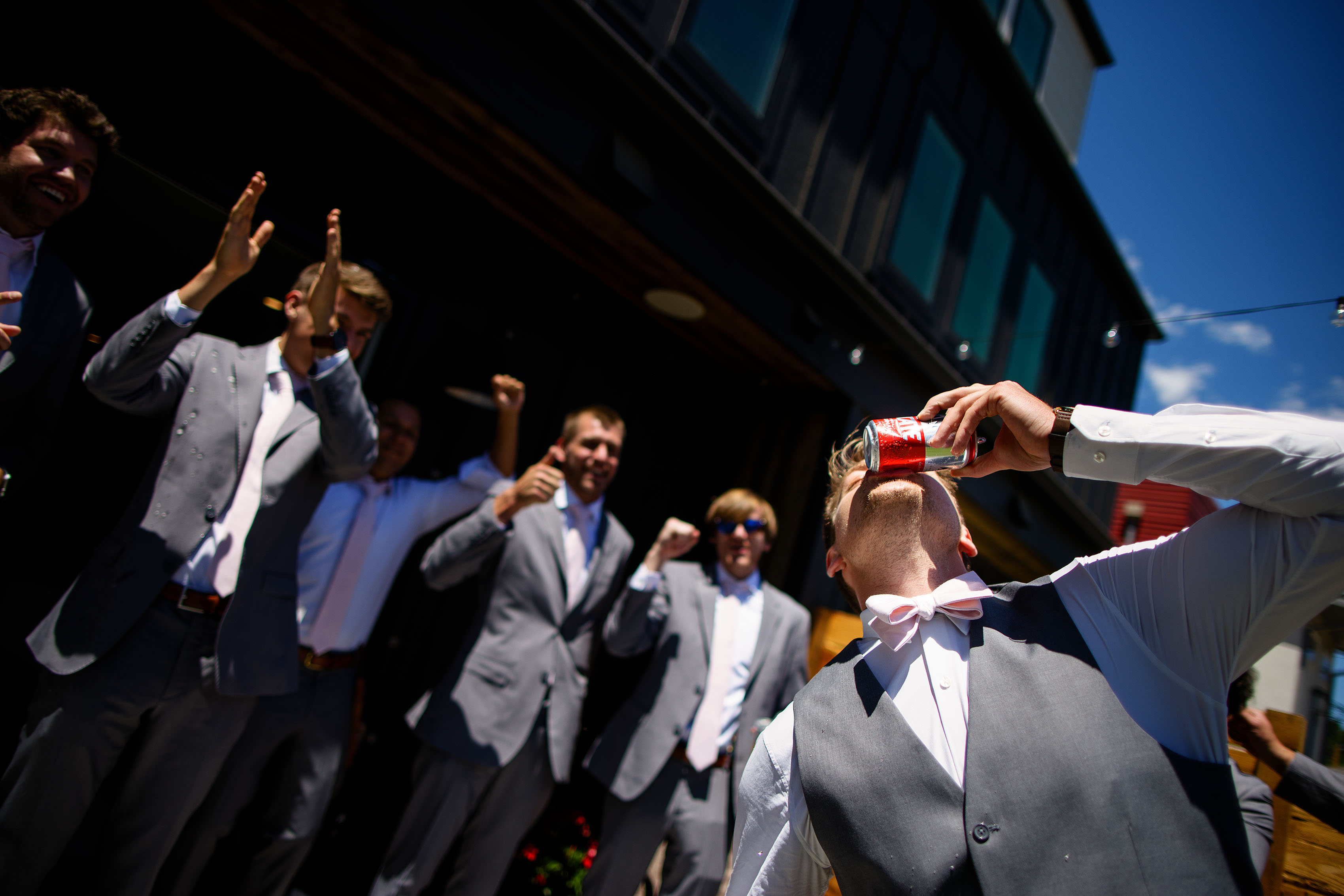 The groom shotguns a beer as groomsmen cheer