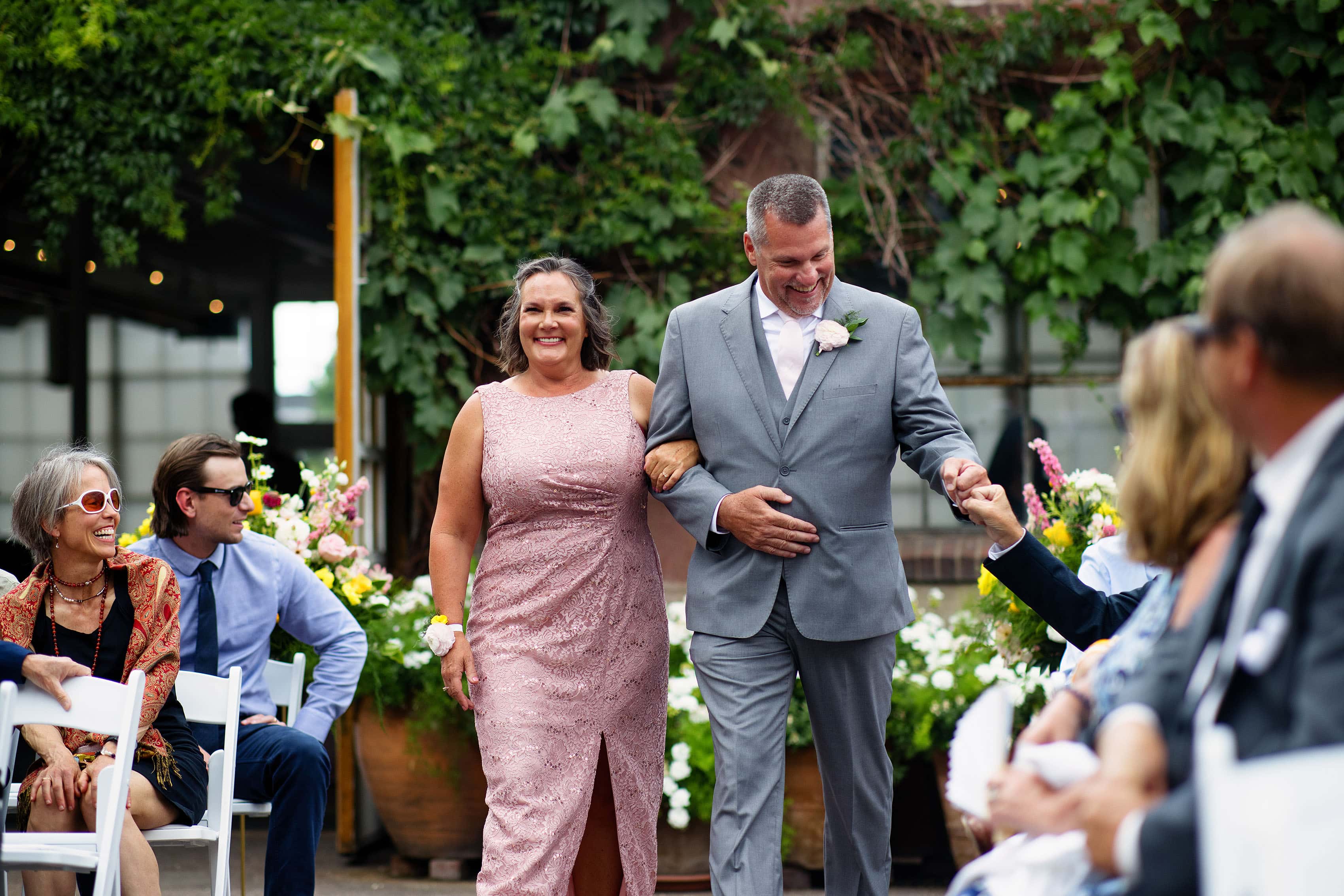 The father of the bride gets a fist bump as he escorts his wife down the aisle