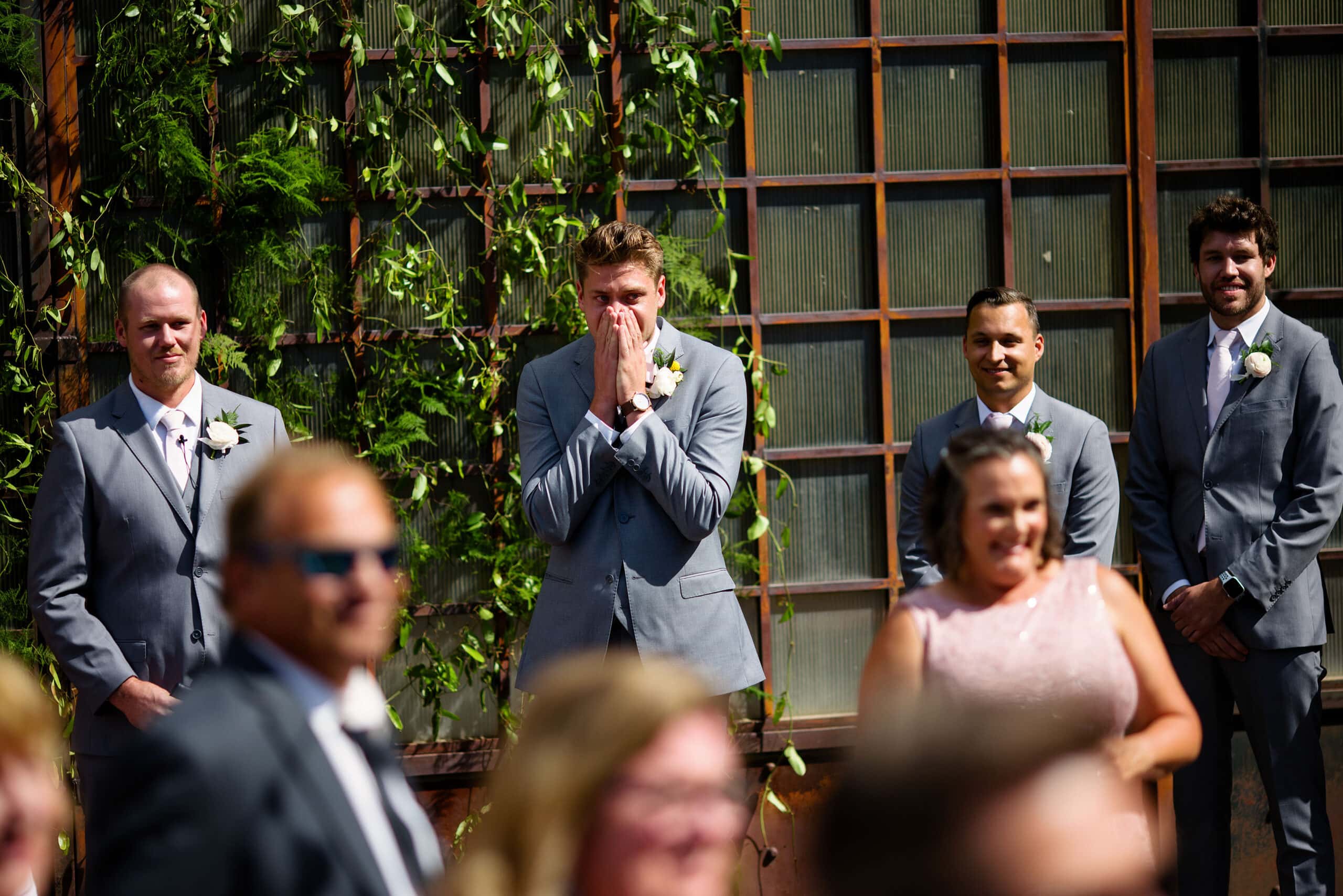 The groom reacts as the bride walks down the aisle