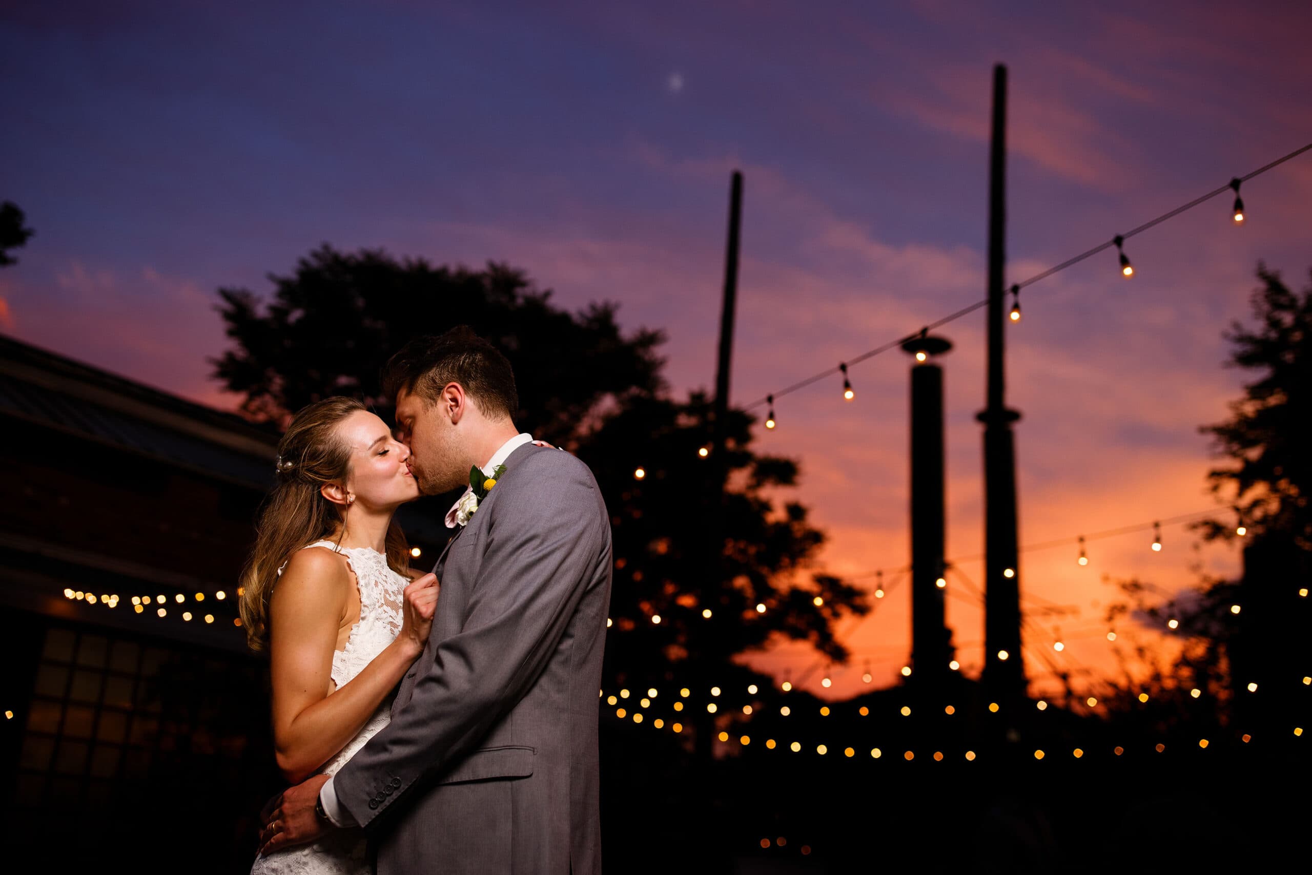 Newlyweds share a kiss at sunset under the market lights at Blanc on their wedding day in Denver