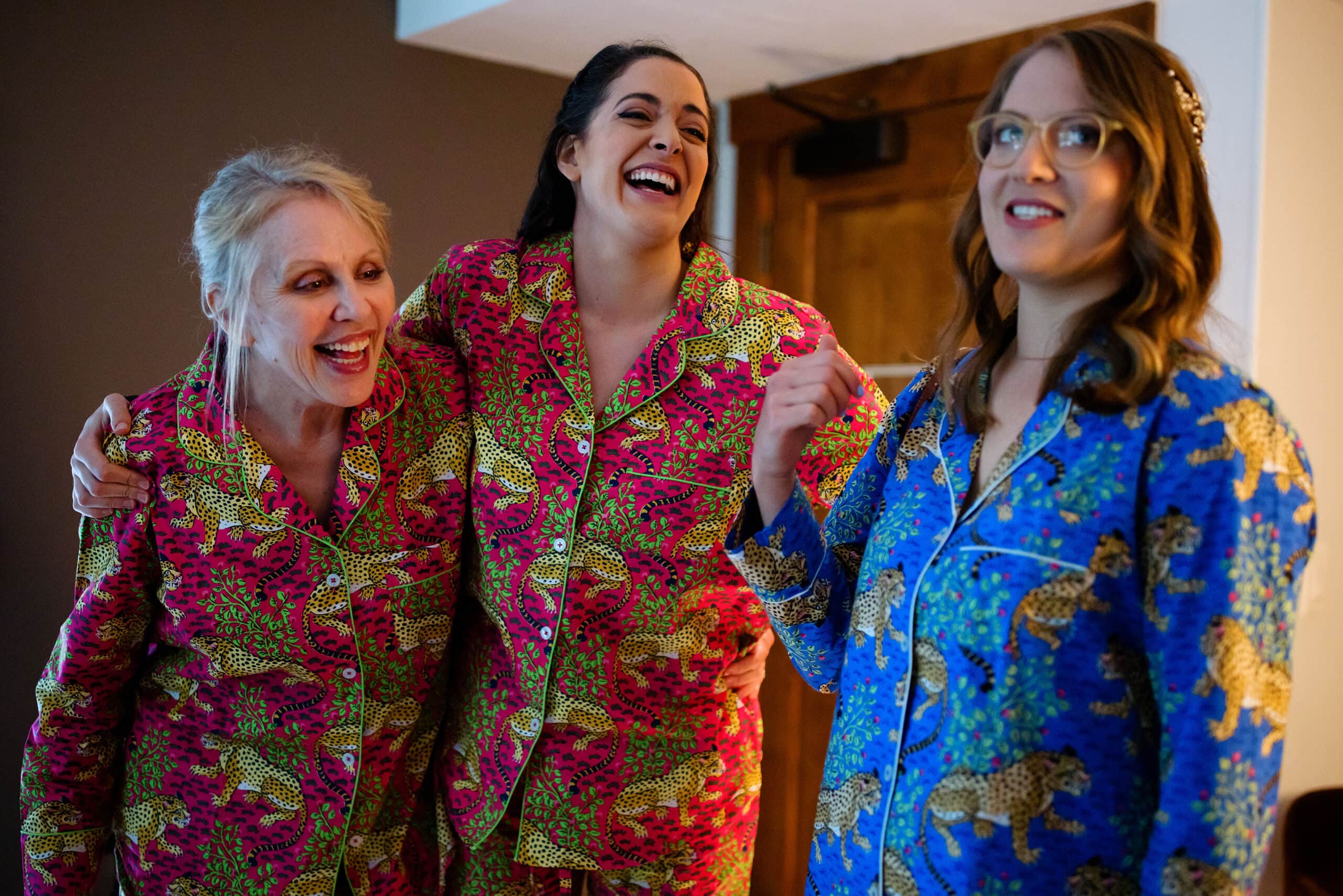 The bride, sister and her mother laugh together while getting ready
