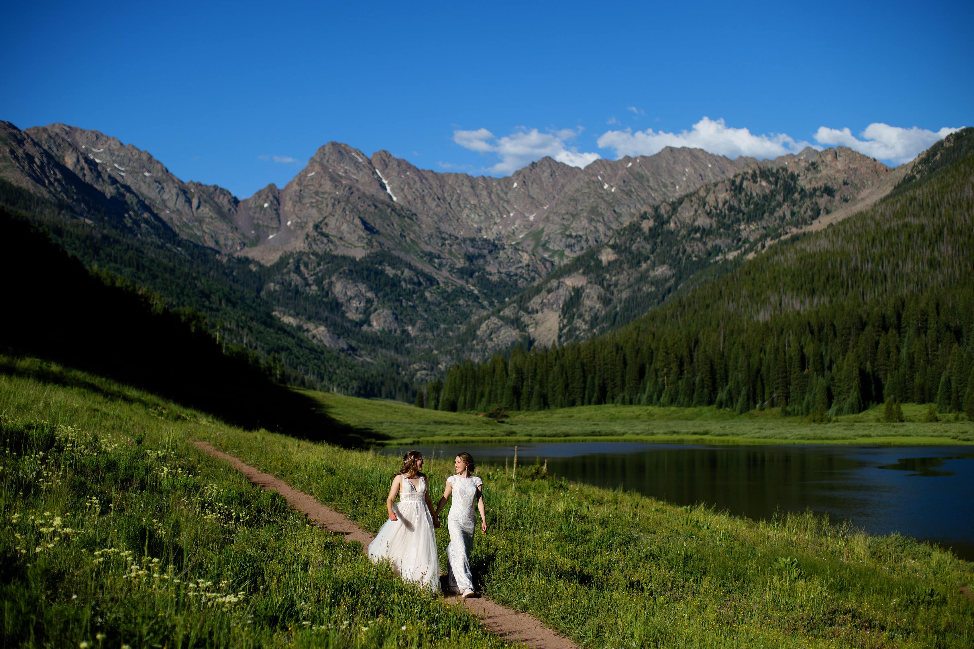 The brides walk together on the trail at Piney River Ranch