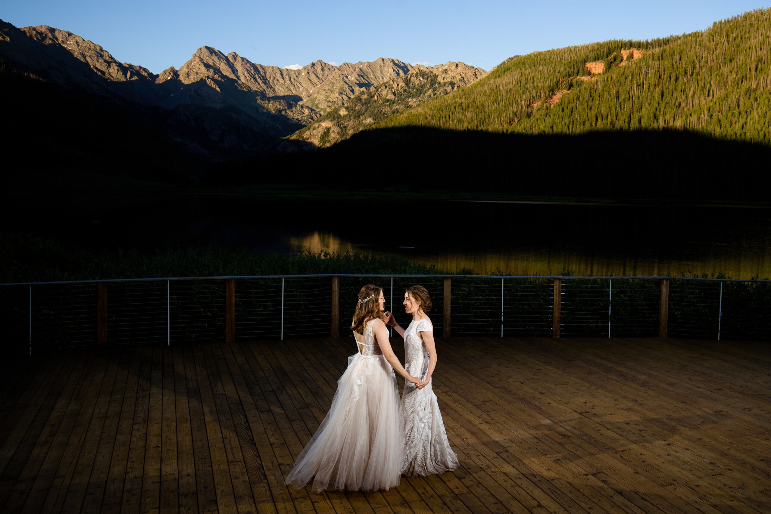 The two brides share their first dance on the dock at Piney River Ranch as the sun illuminates the Gore Range