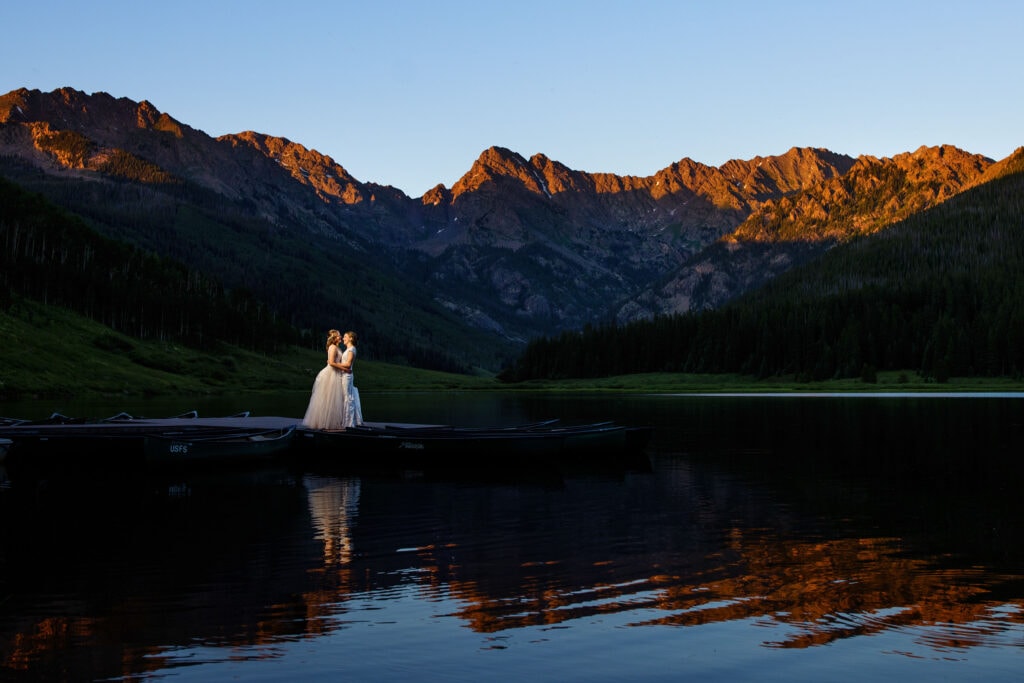 The newlyweds pose on the dock as alpenglow illuminates the Gore Range at Piney River Ranch